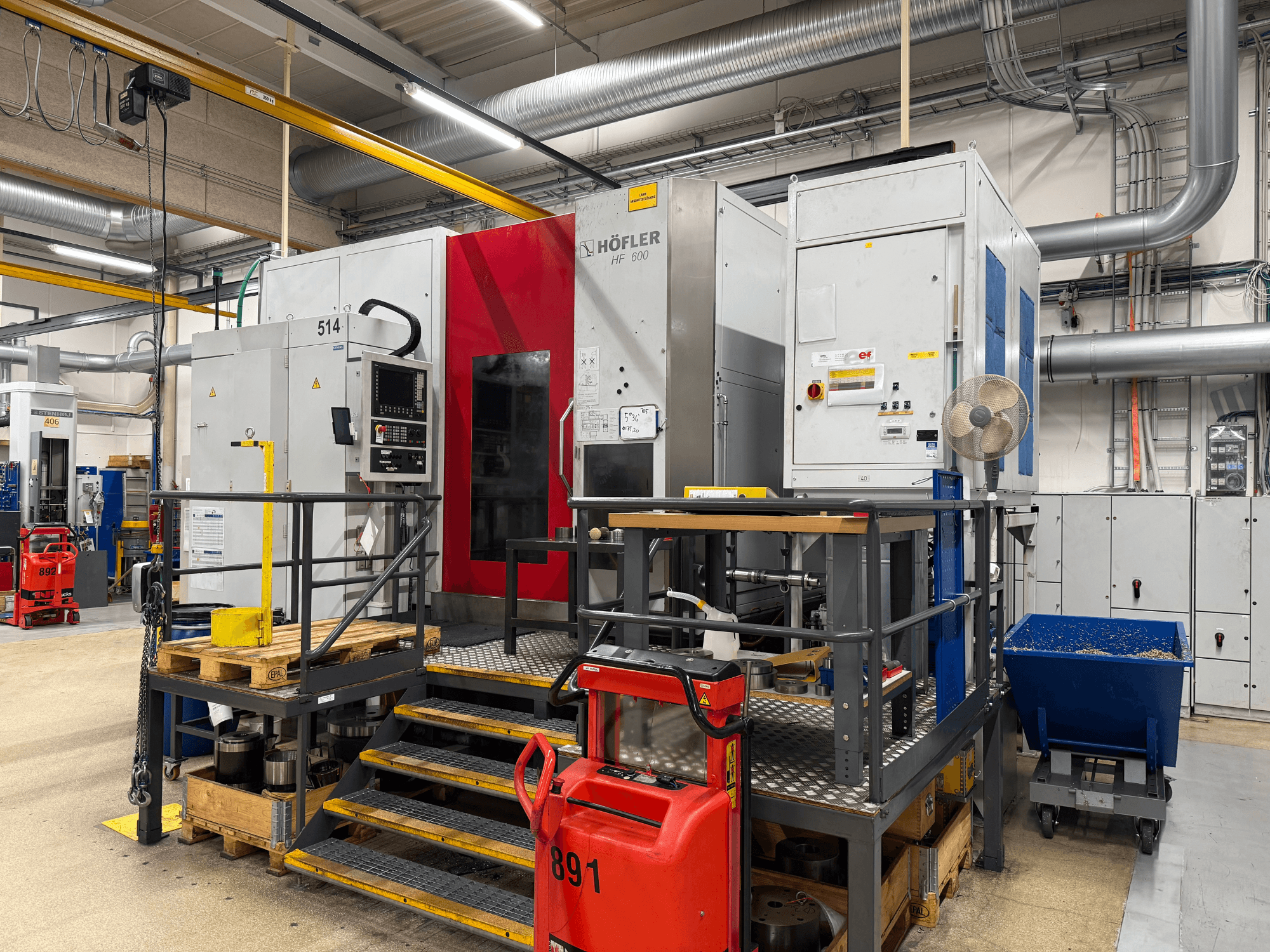 HOFLER HF 600 Werkzeugmaschine, Seitenansicht, zeigt Bedienfeld, gelbe Sicherheitsbarriere und die Umgebung der Werkstatt.