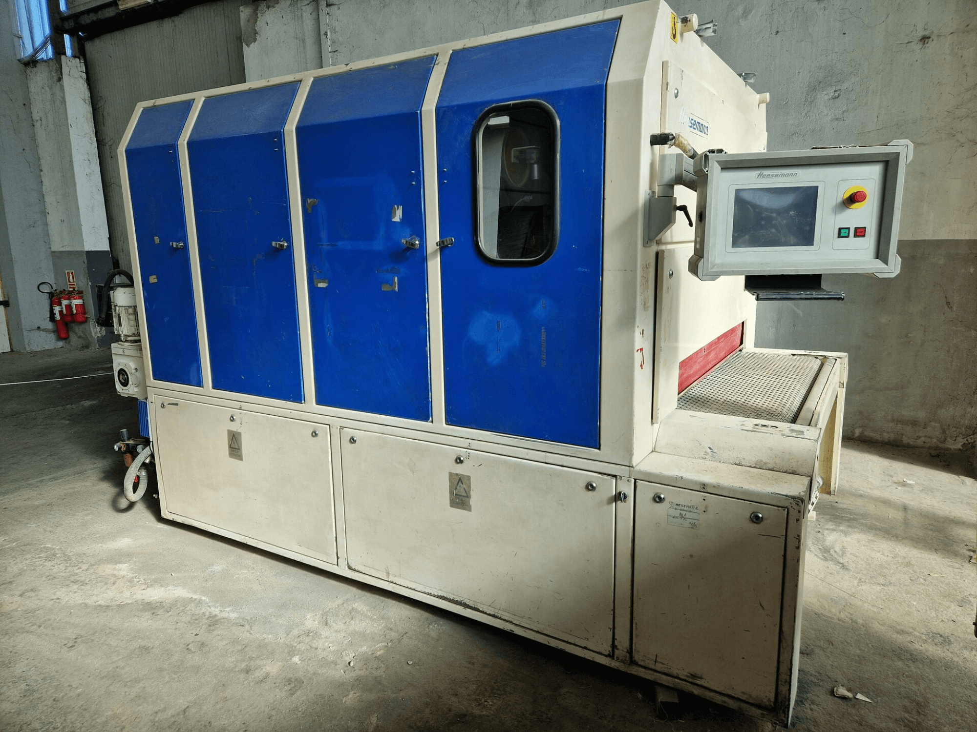 Industriemaschine der Marke "Sedecom", Seitenansicht; mit blauen Paneelen, einem Kontrollbildschirm und einer strukturierten Oberfläche zur Handhabung von Produkten.