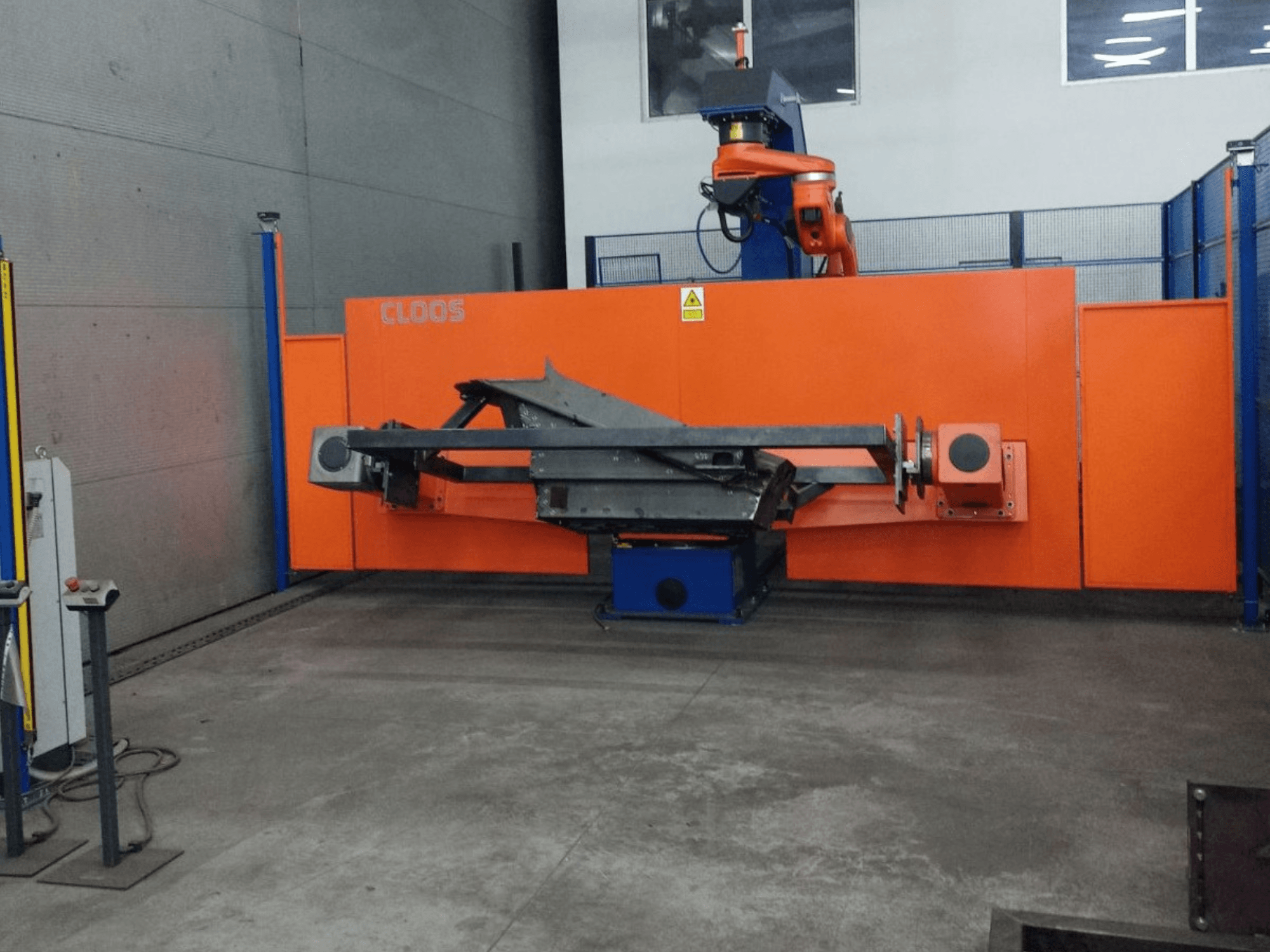 Frontansicht des CLOOS QIROX QRC-350-E Automatisierungssystems mit Roboterarm und Metallstruktur in einer industriellen Umgebung.