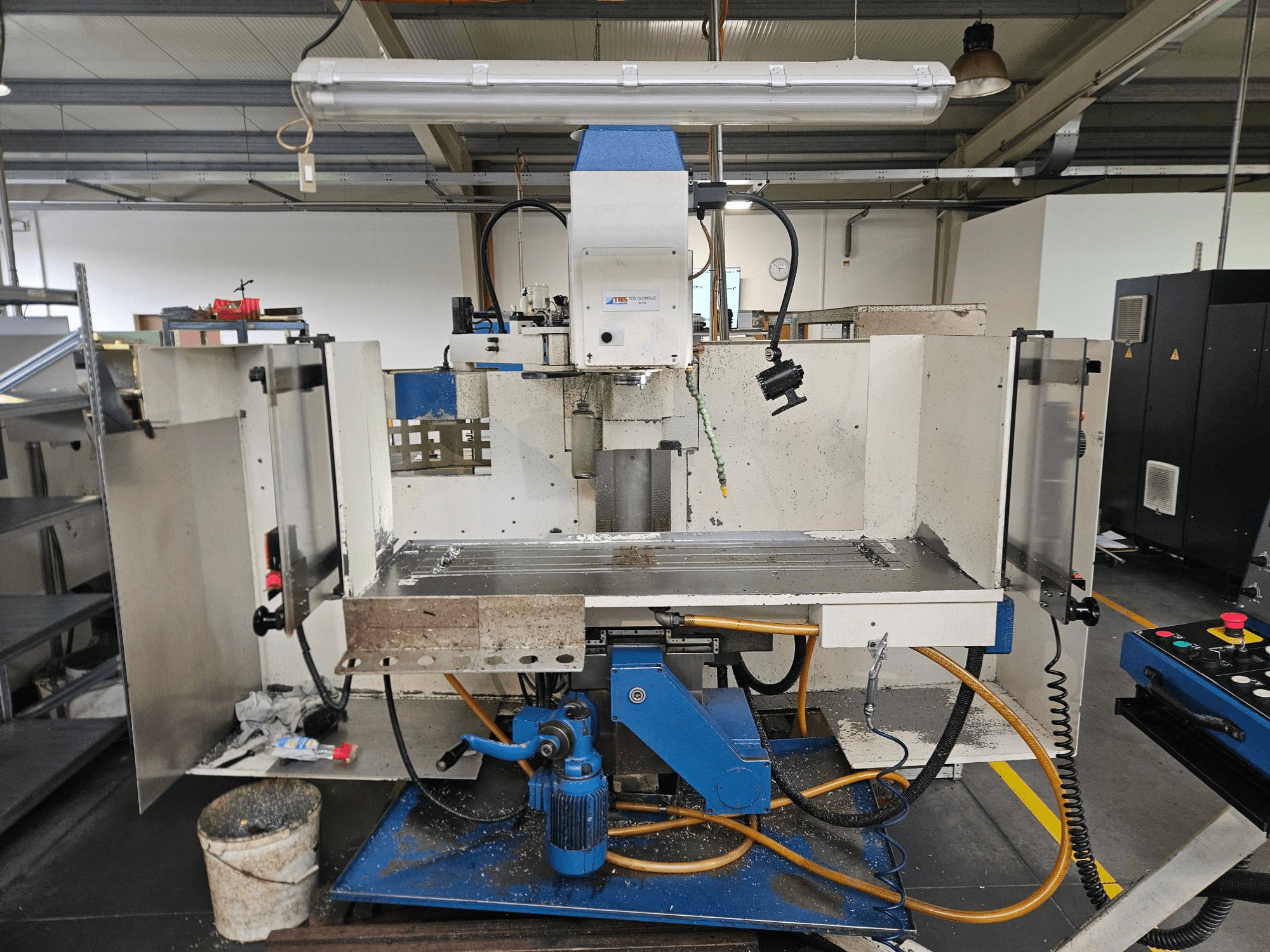 TOS Olomouc FV30 CNC Ein vertikales Bearbeitungszentrum in einer Werkstatt, Vorderansicht mit Bedienfeld, Arbeitstisch und Kühlmittelanlage.
