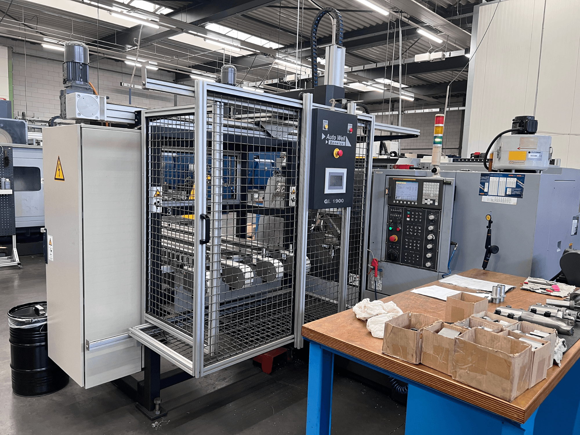 Vorderansicht der Auto Weld GL 1900 Maschine mit Bedienfeld, Sicherheitsabdeckung und Werkzeugen auf einer Werkbank.