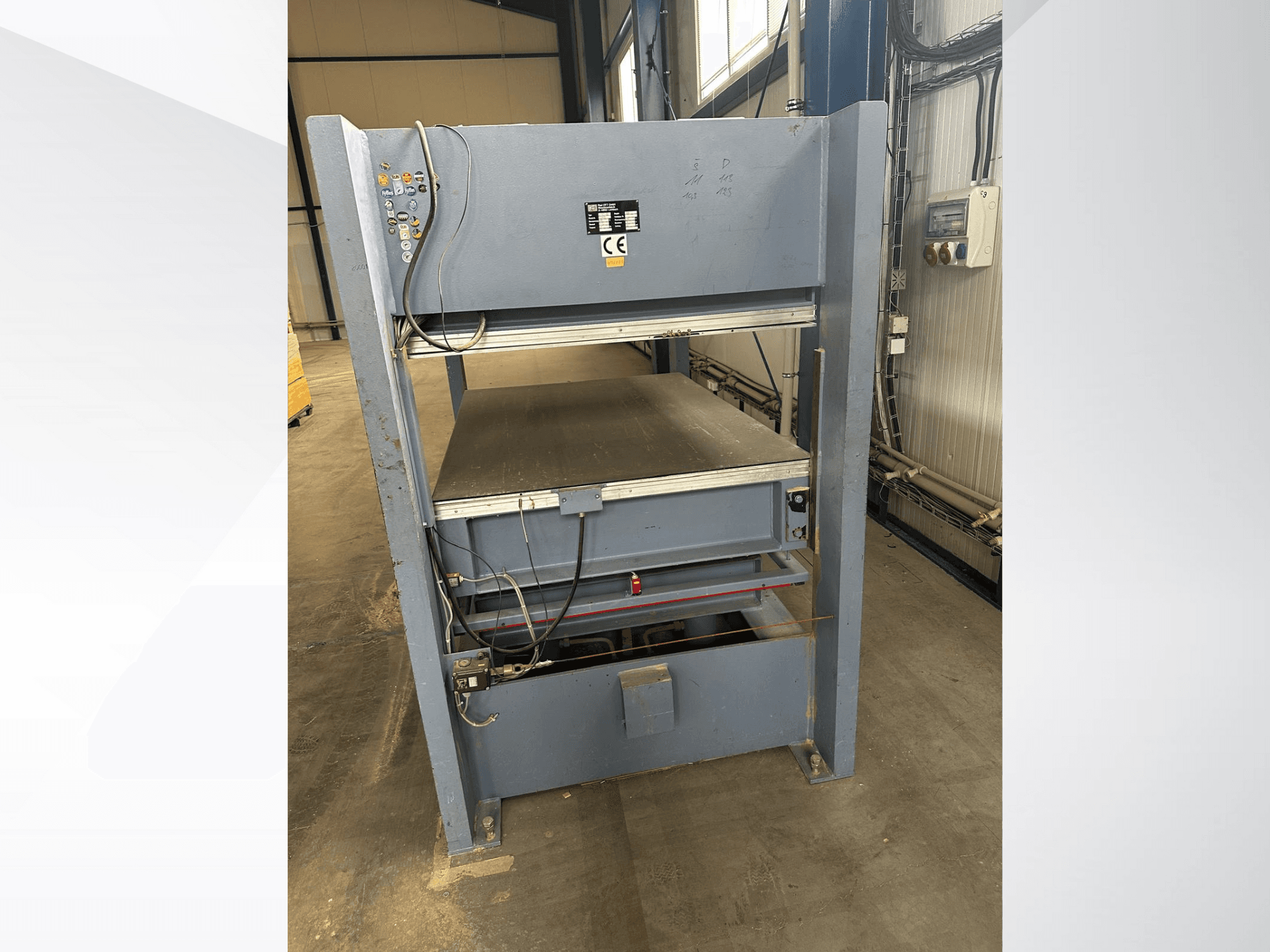 Graue Industriemaschine mit Bedienfeld, von vorne gesehen; mit verstellbaren Plattformen und Sicherheitsmarkierungen.