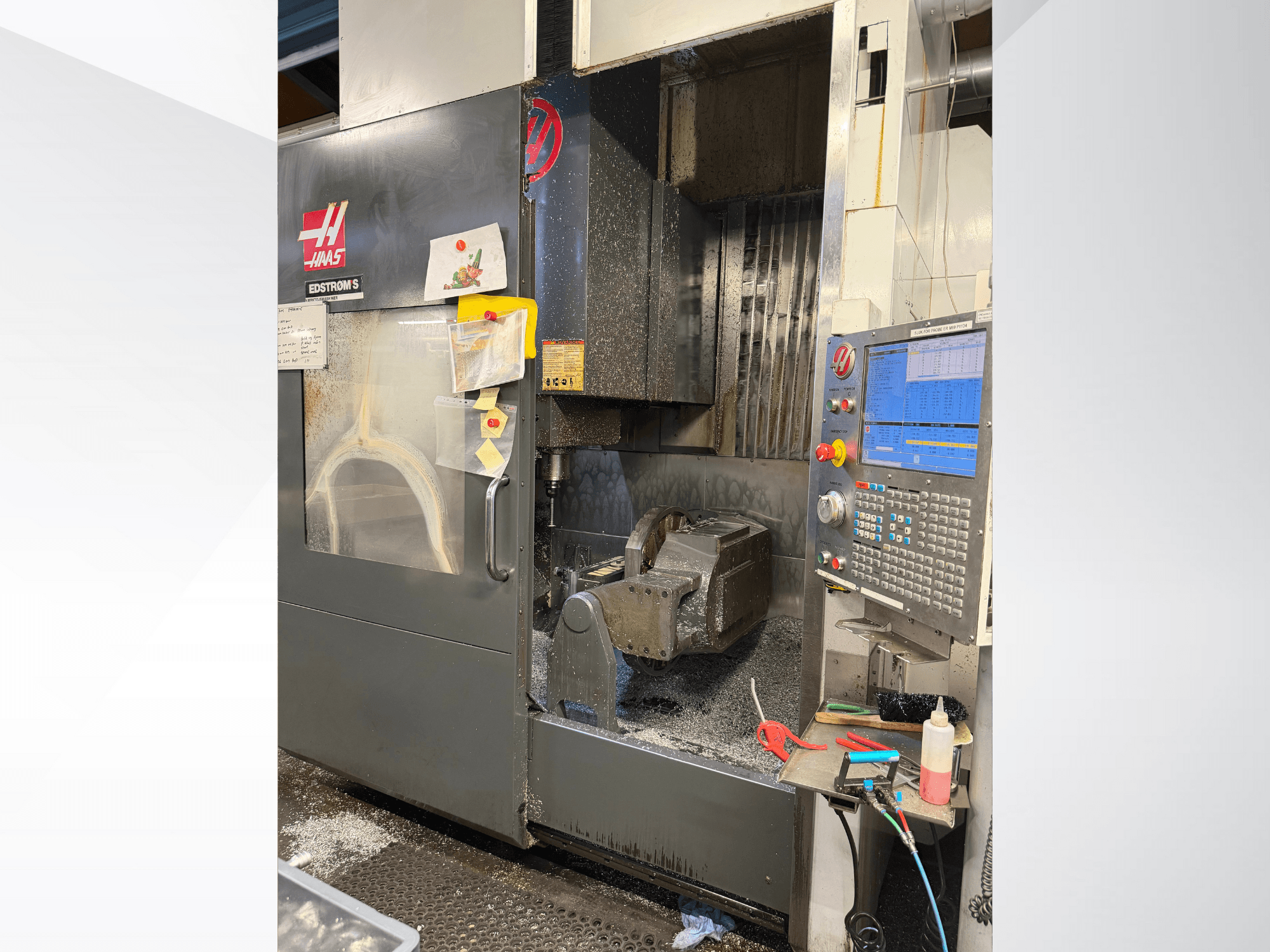 Haas CNC-Maschine Modell EDSTROM S, Vorderansicht, mit Metallwerkstück, Bedienfeld und Metallspänen im Inneren.