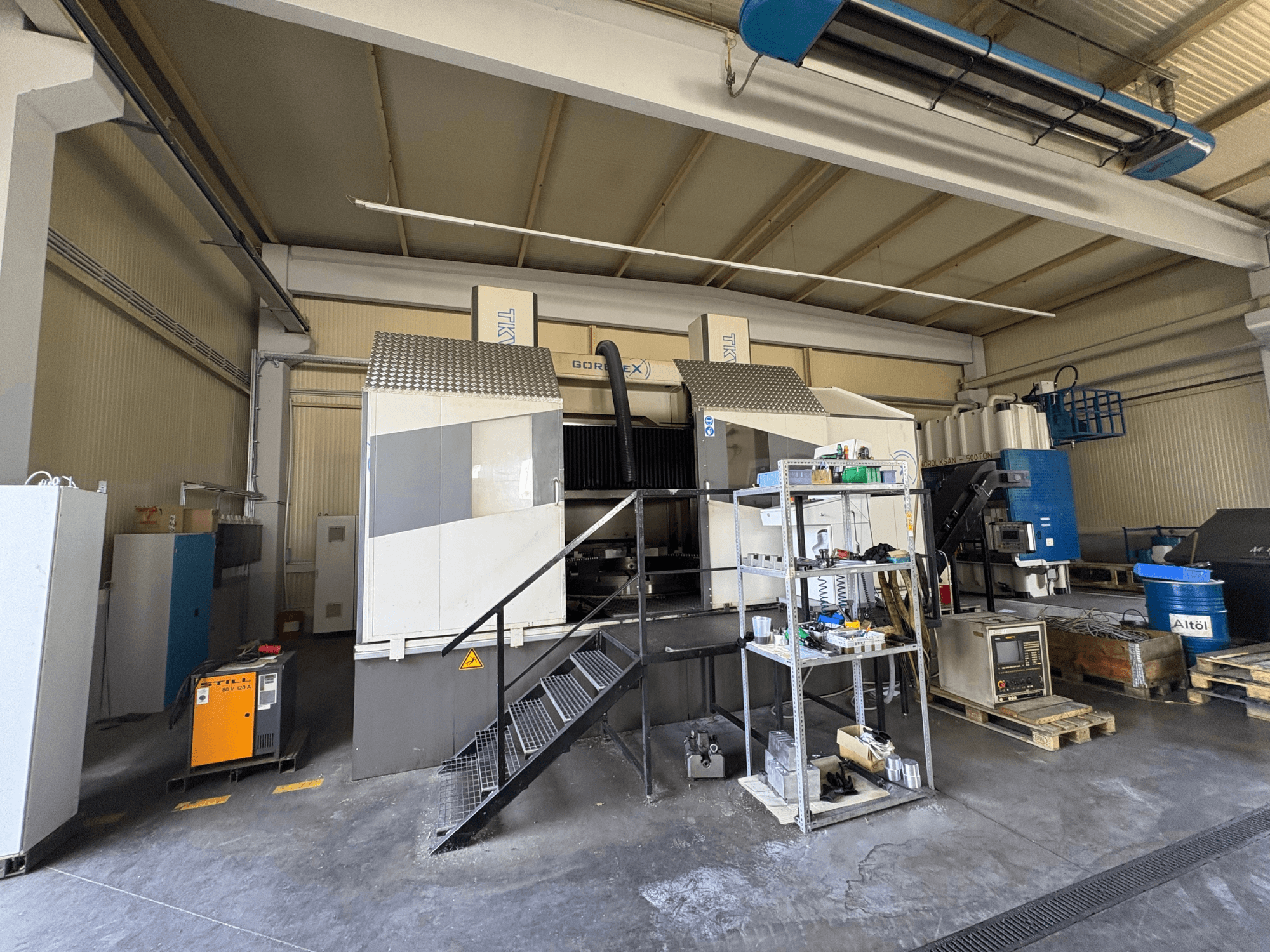 Industrielle Bearbeitungseinrichtung mit GORAT X-Maschine, Seitenansicht; mit Werkzeugen, Bedienfeld und Ausrüstung auf Regalen.