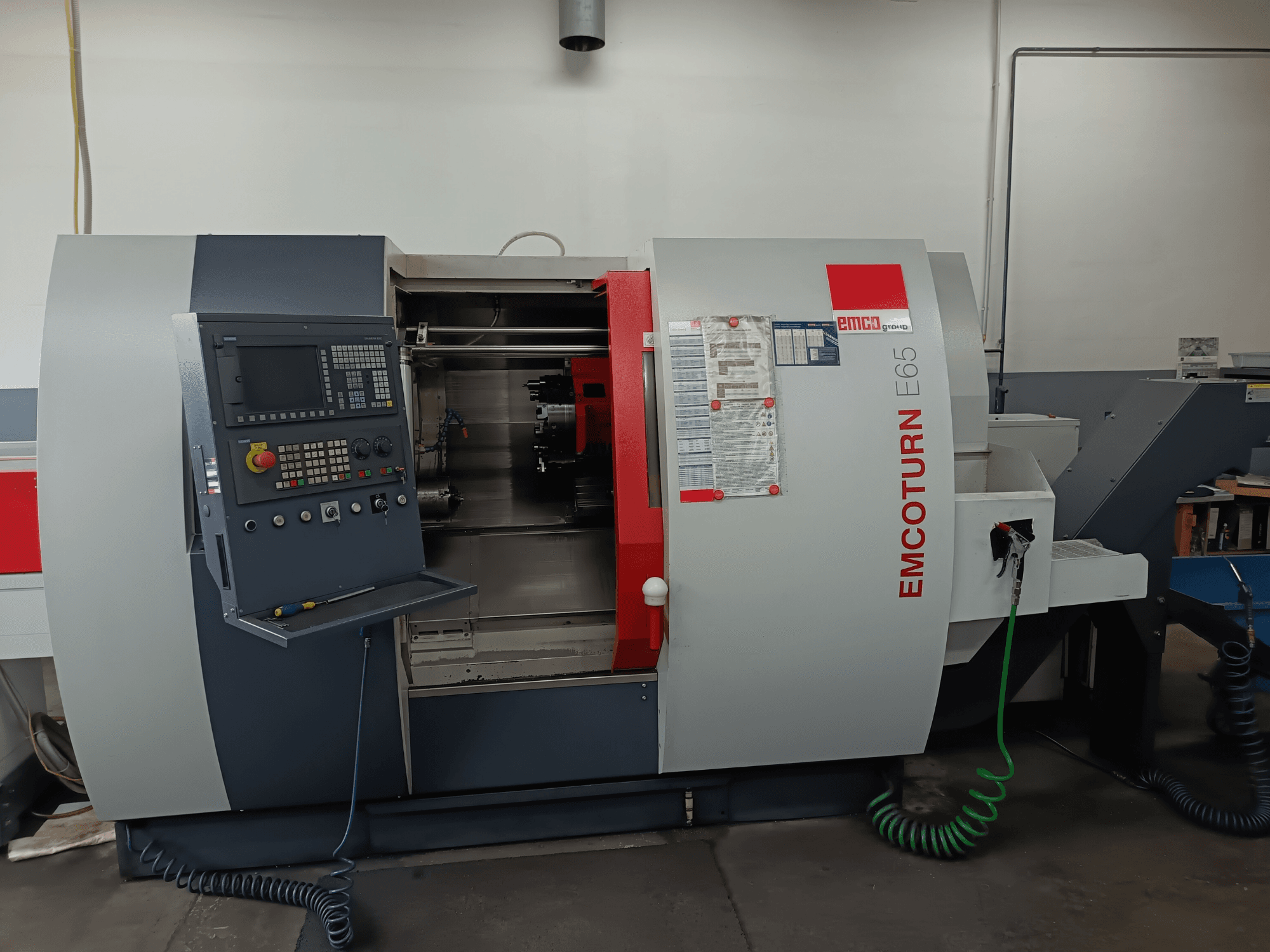 EMCO EMCOTURN E65 Dreh-Fräszentrum, Vorderansicht mit Bedienfeld, internem Mechanismus und Funktionen in einer Werkstattumgebung.