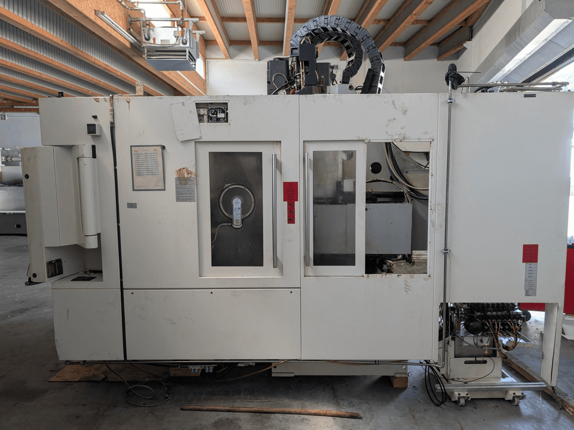 Vertikales Bearbeitungszentrum STAMA MC 326, Seitenansicht mit Bedienfeld, Spindelbereich und verschiedenen Aufklebern an der Maschine.