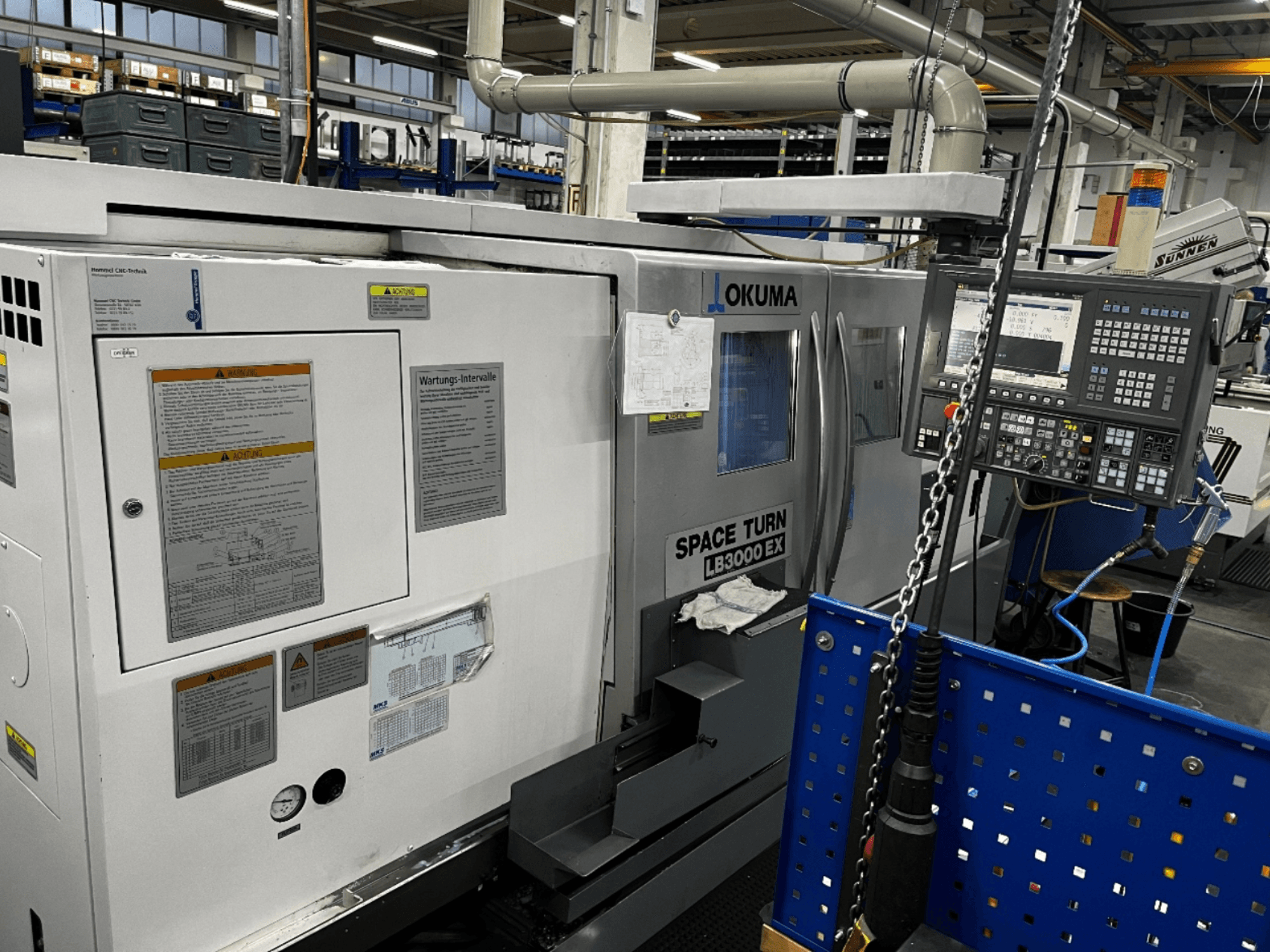 Okuma LB3000 EX Horizontaldrehmaschine, Vorderansicht, mit Bedienfeld und Sicherheitshinweisen an der Seite.
