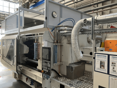 Industriemaschine von Brand X, Seitenansicht mit Bedienfeld, Rohrleitungen und Maschinenkomponenten in einer Fabrikumgebung.