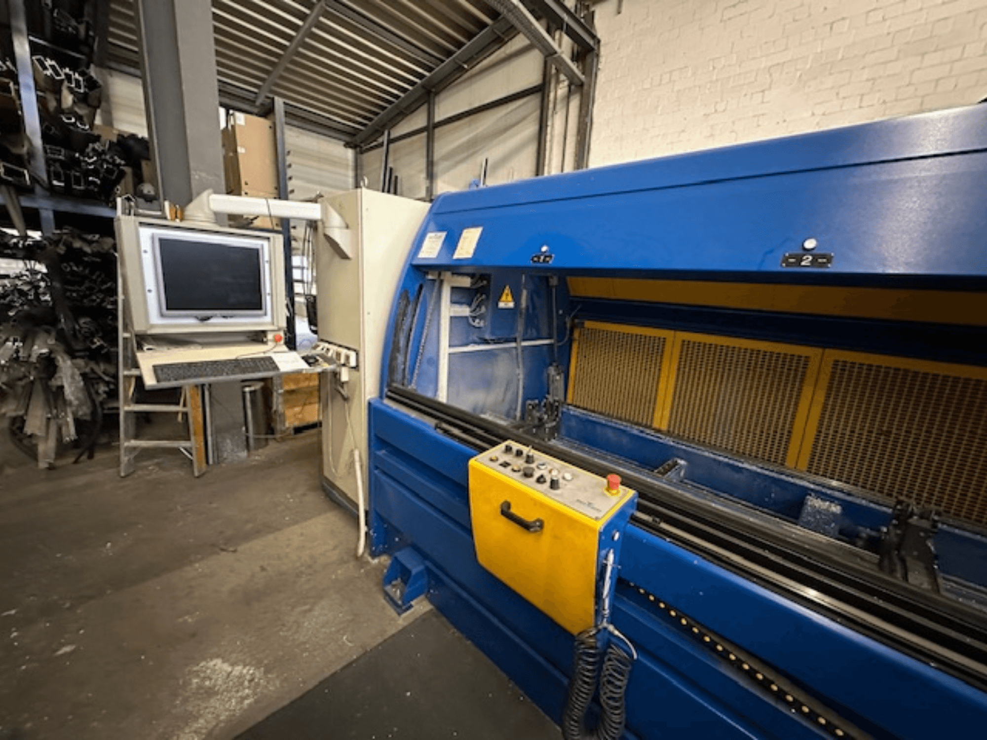 Frontansicht des SCHÜCO Profilbearbeitungscenter 299 650, ein Universalbearbeitungszentrum mit Steuerung und Computerarbeitsplatz.