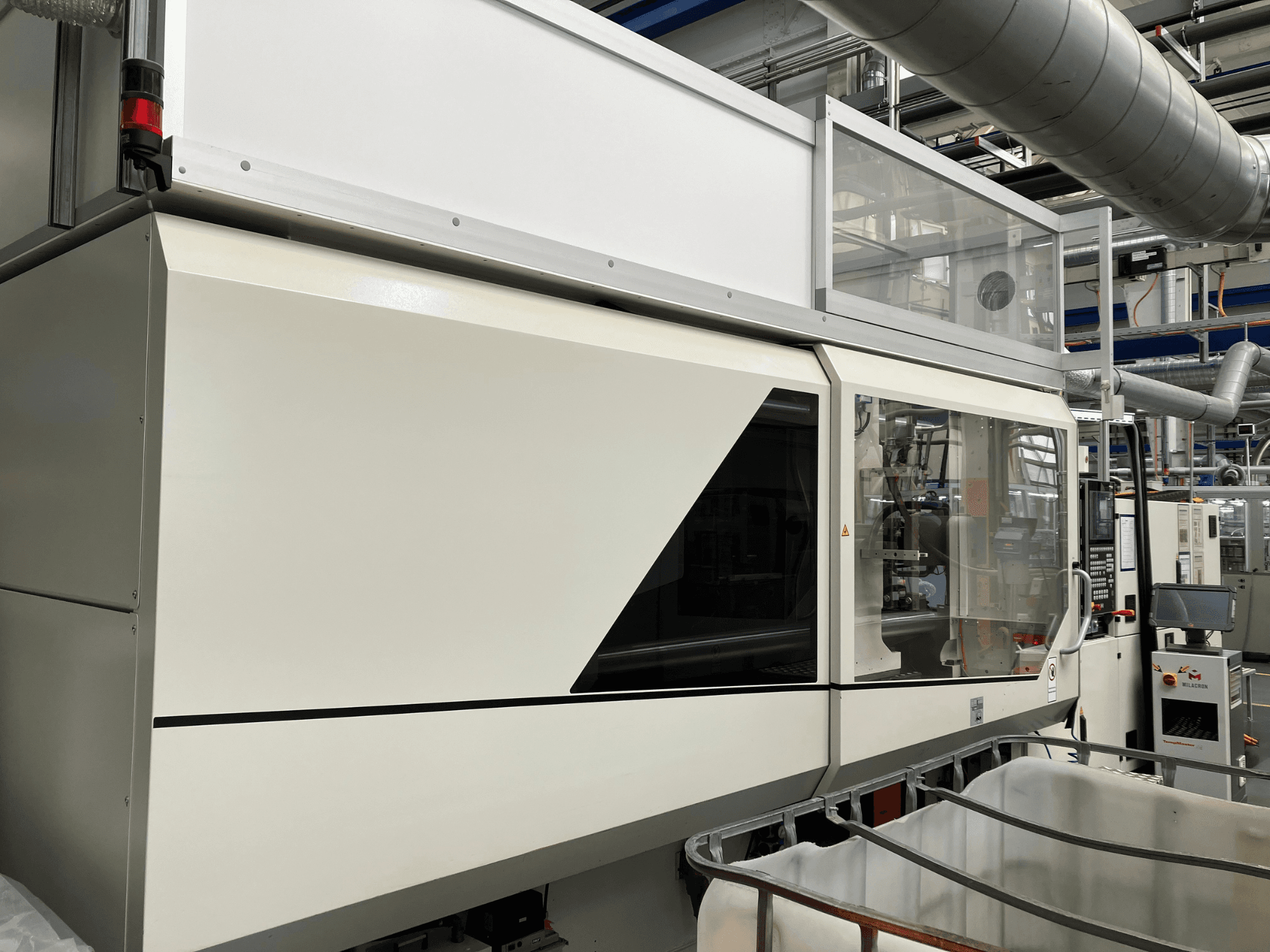 Vorderansicht der Industriemaschine mit elegantem weißem Design, Anzeigetafel und Glasbereich zur besseren Sichtbarkeit der Komponenten.