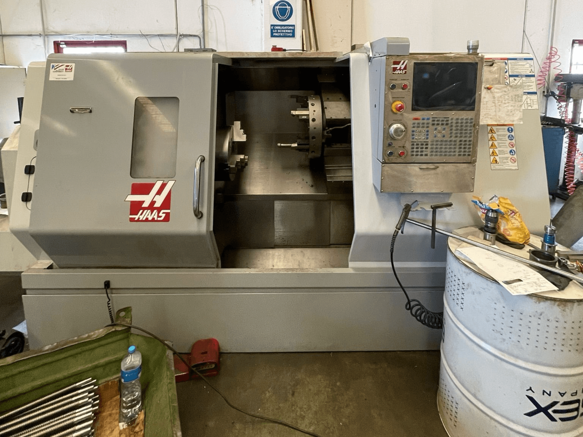 HAAS SL-30TBHE Horizontaldrehmaschine in der Vorderansicht, mit Bedienfeld, großer Ladetür und verschiedenen Werkzeugen in der Nähe.