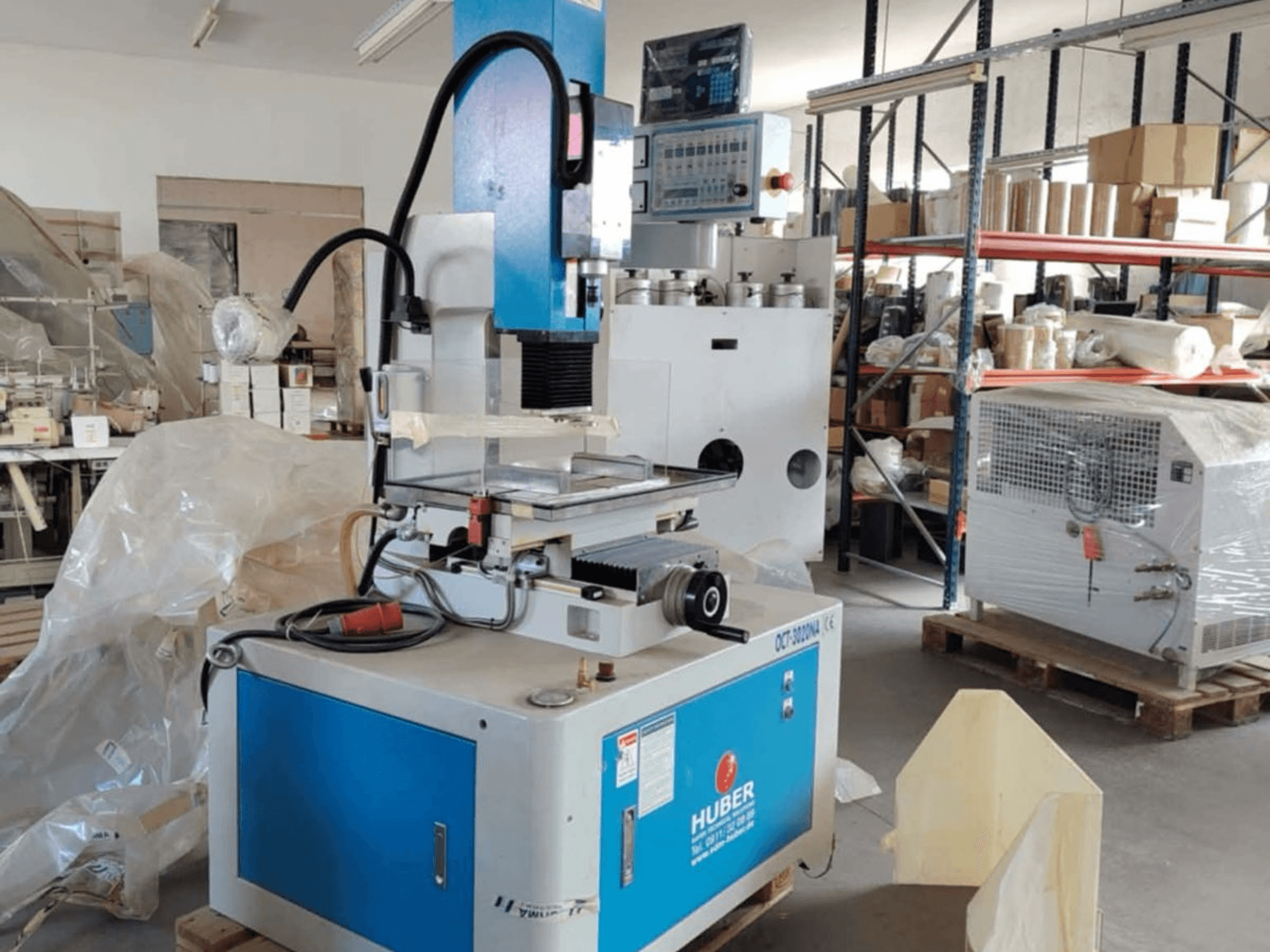 HUBER OCT-3020 NA Senkerodiermaschine in einer Werkstatt, Vorderansicht mit blauem und grauem Gehäuse, digitaler Steuerung und Arbeitsbereich.
