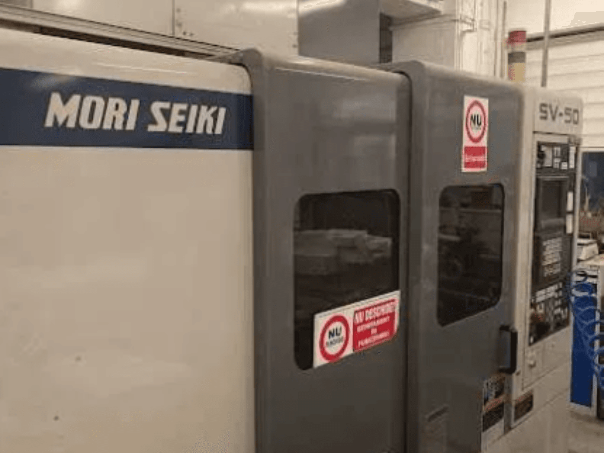 MORI SEIKI SV-50 CNC-Maschine, Seitenansicht; mit Bedienfeld und Sicherheitswarnaufklebern.