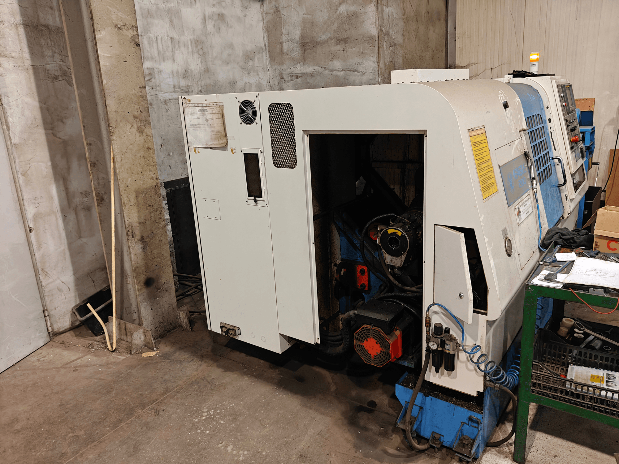 Front view of a lathe machine, brand and model not specified, featuring controls and visible motor components.