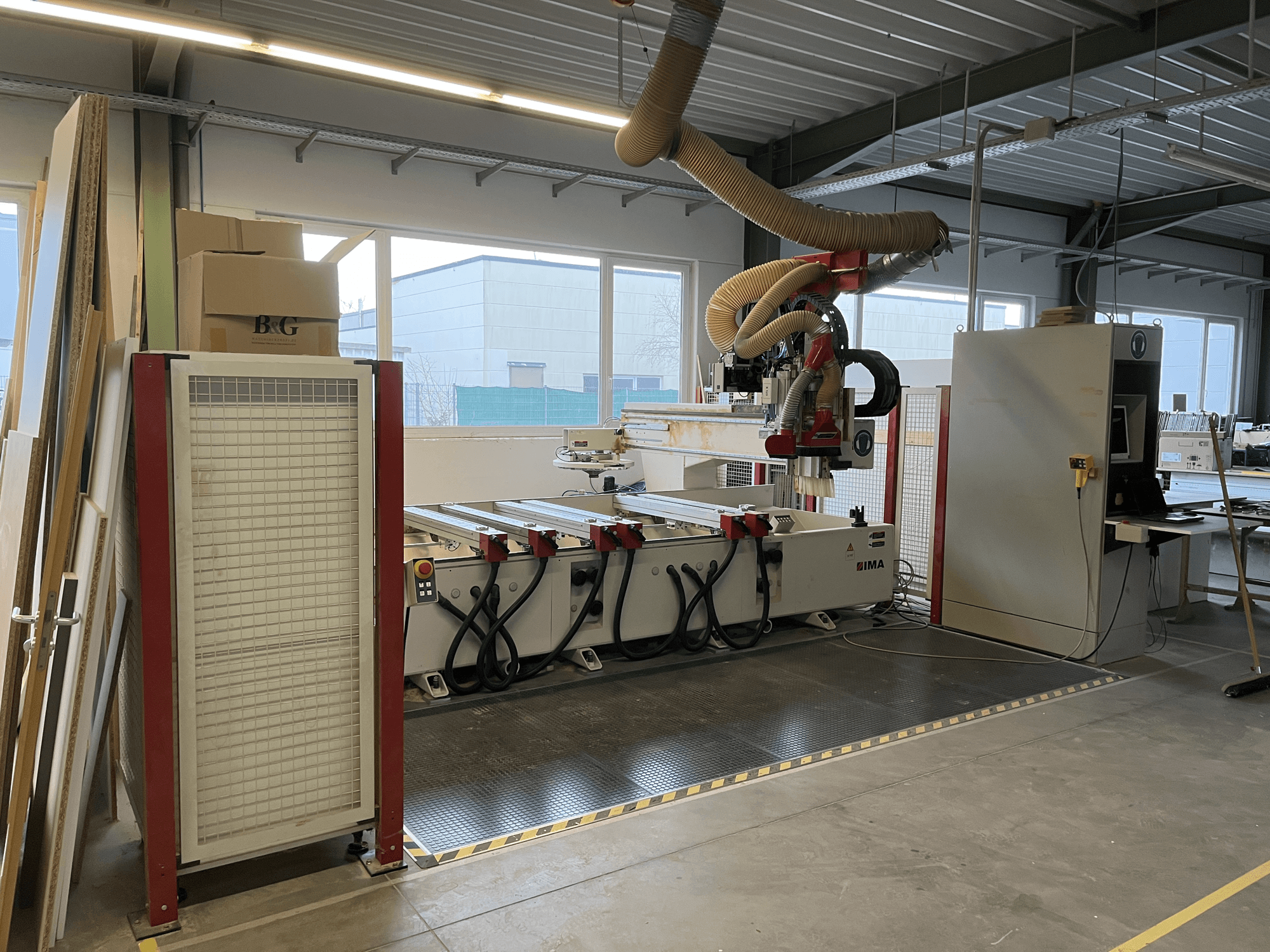 CNC-Holzbearbeitungszentrum IMA BIMA 410 in der Werkstatt, Seitenansicht mit Bedienfeld und Staubabsaugung sichtbar.