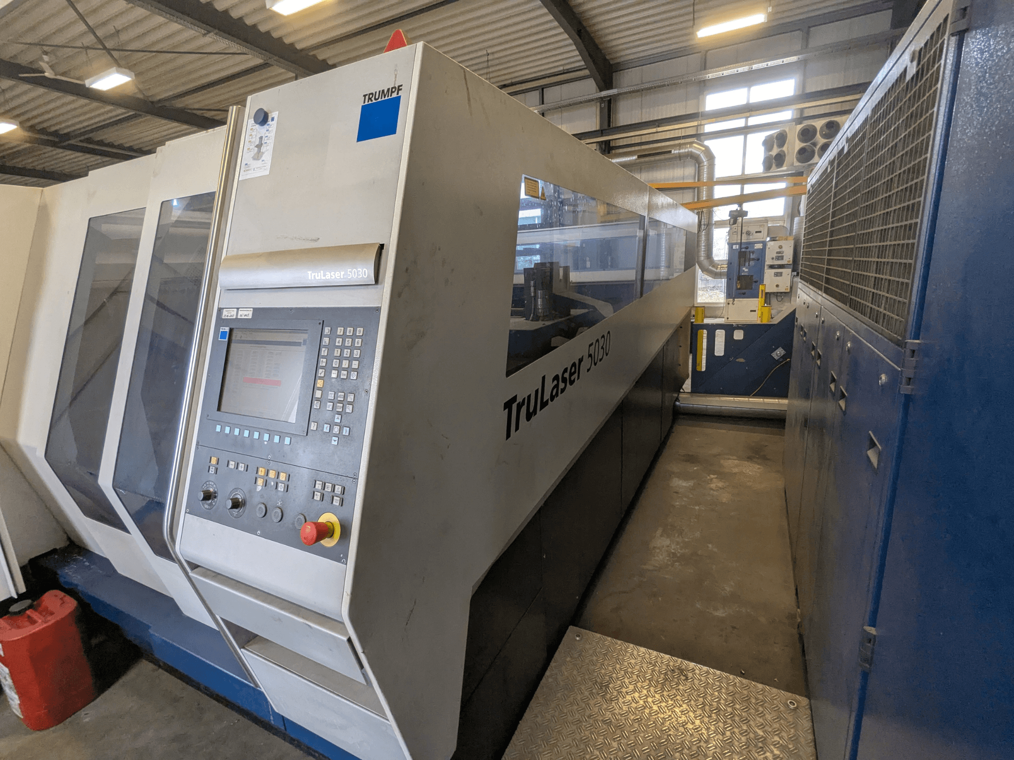 TRUMPF TruLaser 5030 CO2-Laserschneidmaschine, Frontansicht mit Bedienfeld und schlankem Design, in Industrieumgebung.
