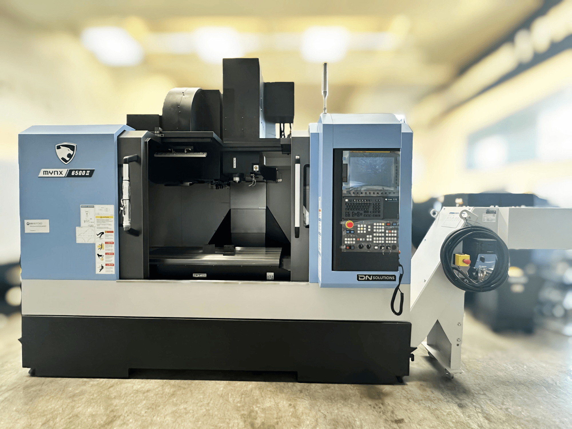 Vertikales Bearbeitungszentrum DN SOLUTIONS MYNX 6500 II, Frontansicht mit Bedienfeld und offenem Bearbeitungsbereich.