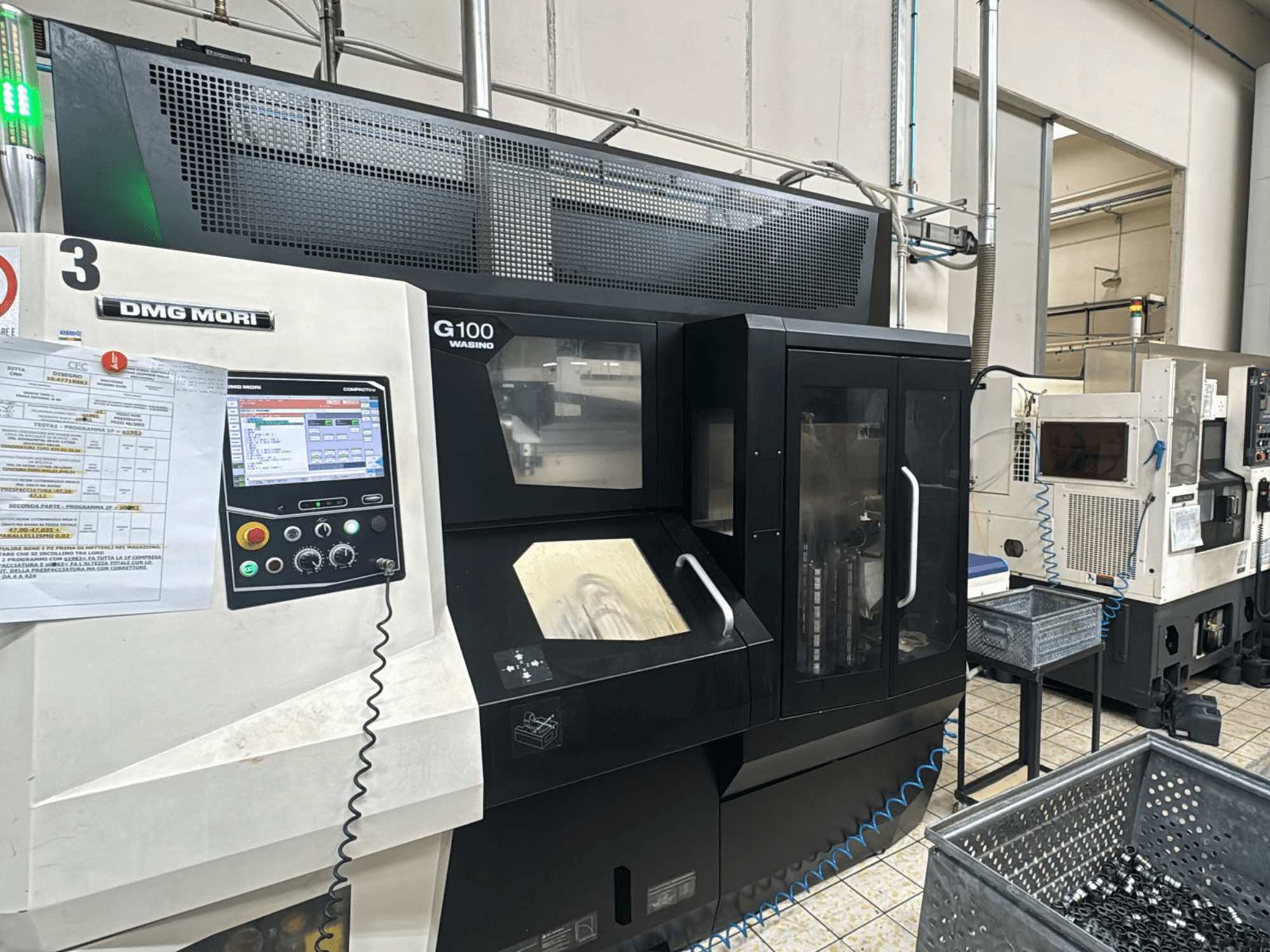 DMG MORI G100 Maschine in einer Fabrik, Vorderansicht, mit digitalem Bedienfeld und nahegelegenen Werkzeugablagefächern.