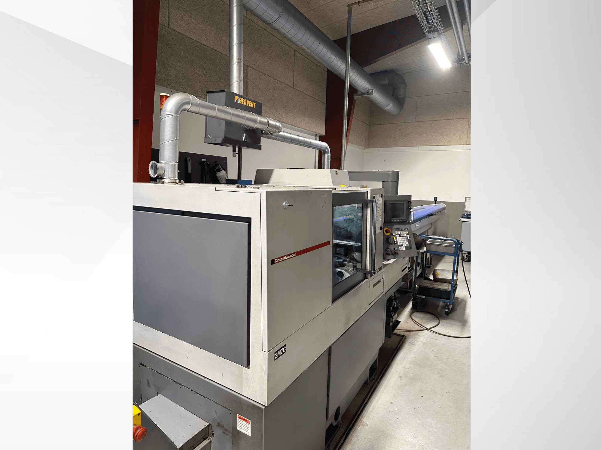 Industriemaschinen der Marke MVC, Seitenansicht mit Bedienfeld und Kanälen, in einer Fabrikumgebung.