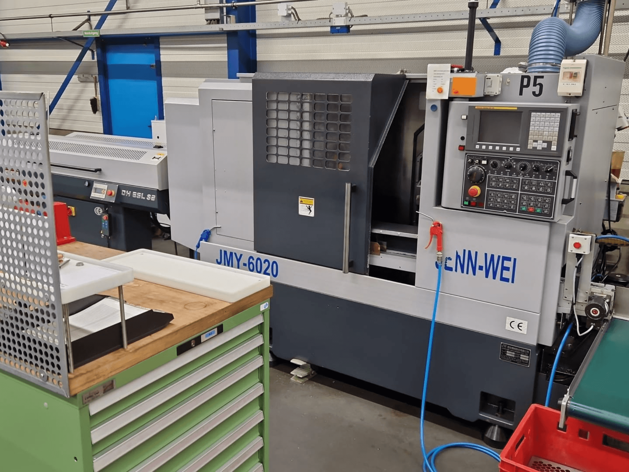 CNC-Drehmaschine, Modell JMY-6020 von cNN-WEI, von vorne gesehen. Mit Bedienfeld, Notausschalter und Kühlmittelleitung.