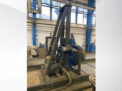 Industriemaschine mit blauem Motor und metallischem Rahmen, von vorne gesehen in einer Werkstattumgebung.