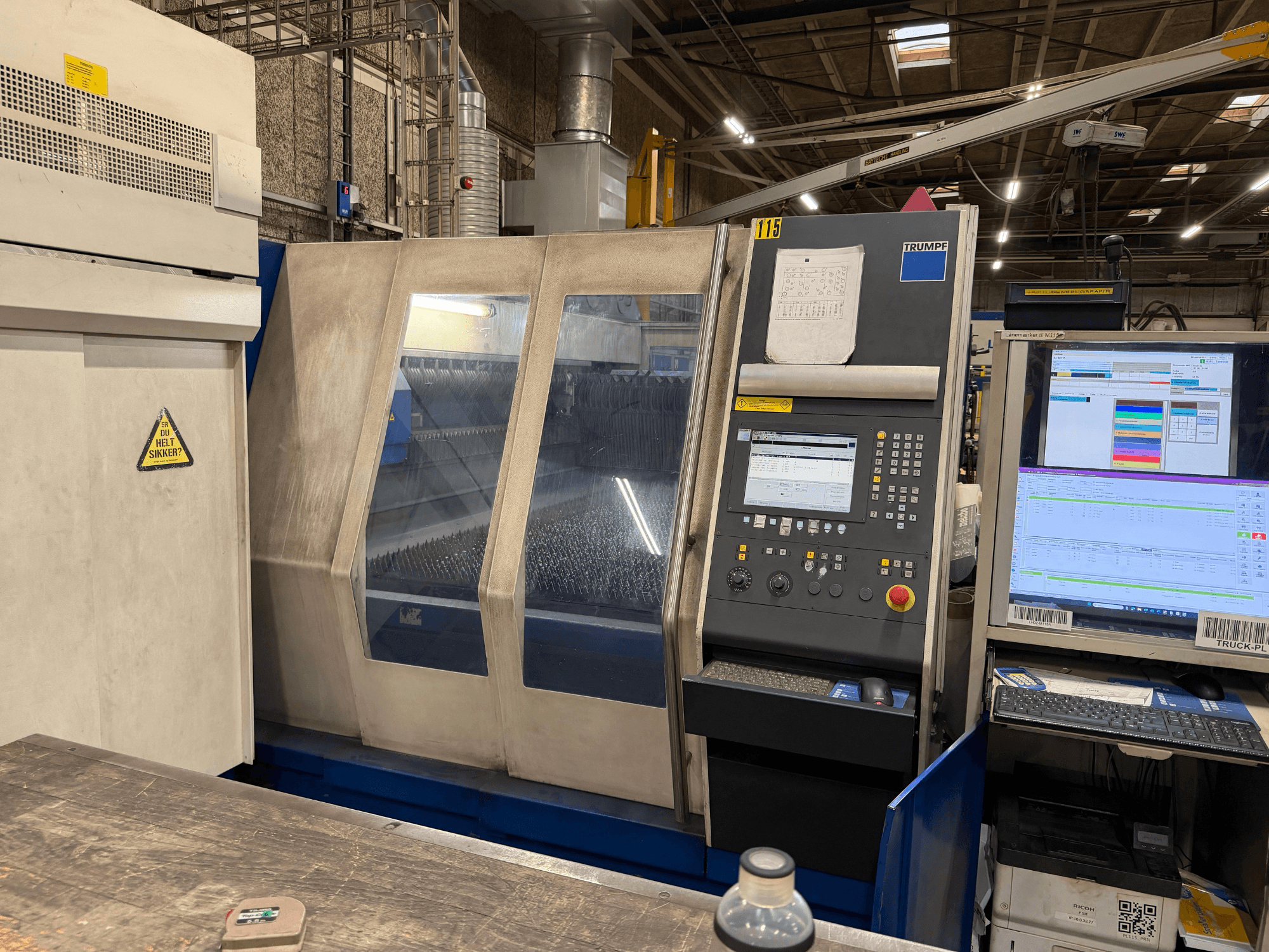 Frontansicht einer industriellen Lasermaschine von Trumpf mit Bedienfeld und digitalen Anzeigen in einer Fabrikumgebung.