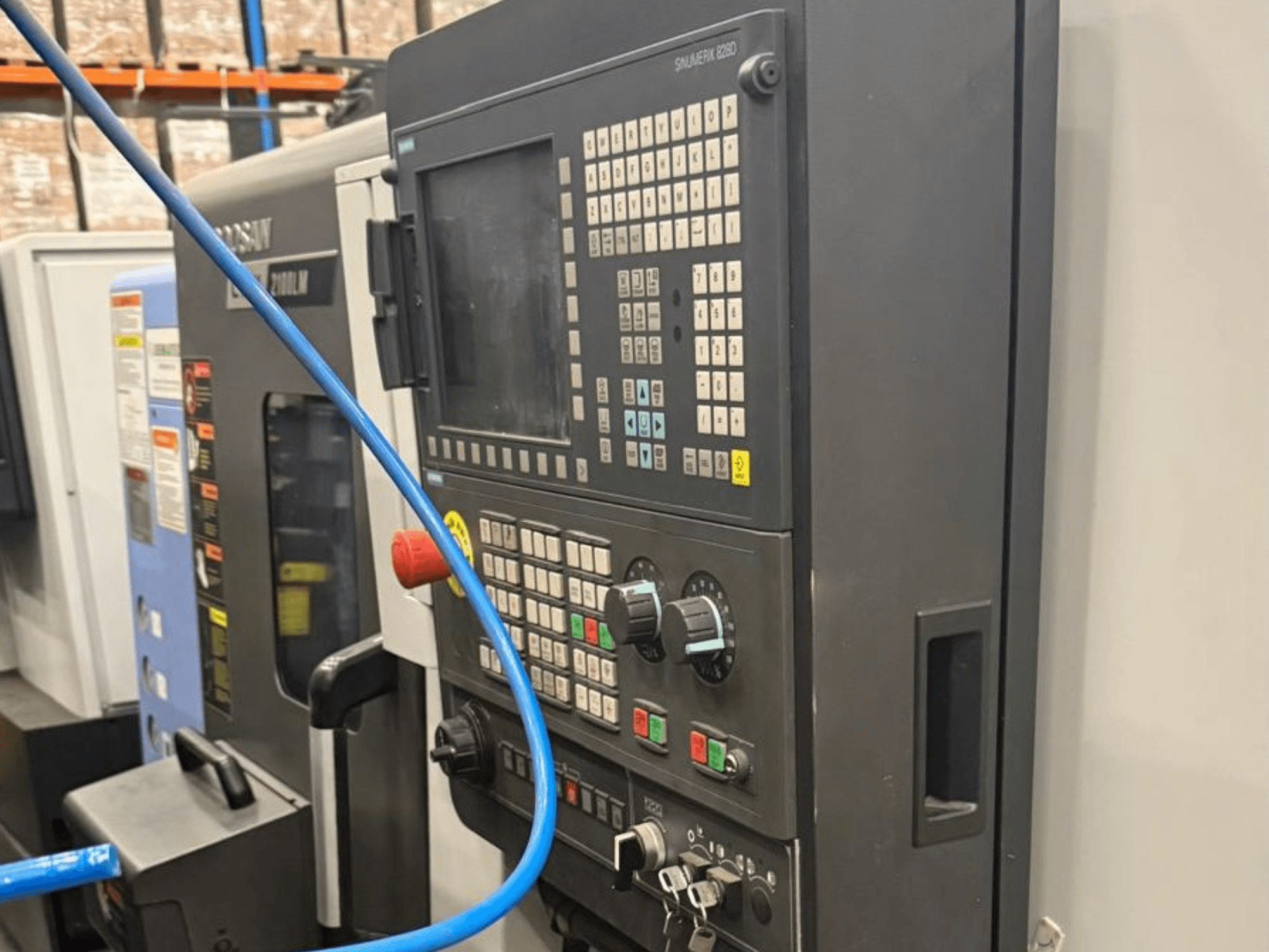 Control panel of a machining tool, front view, featuring buttons, knobs, and a digital display for precise operation.