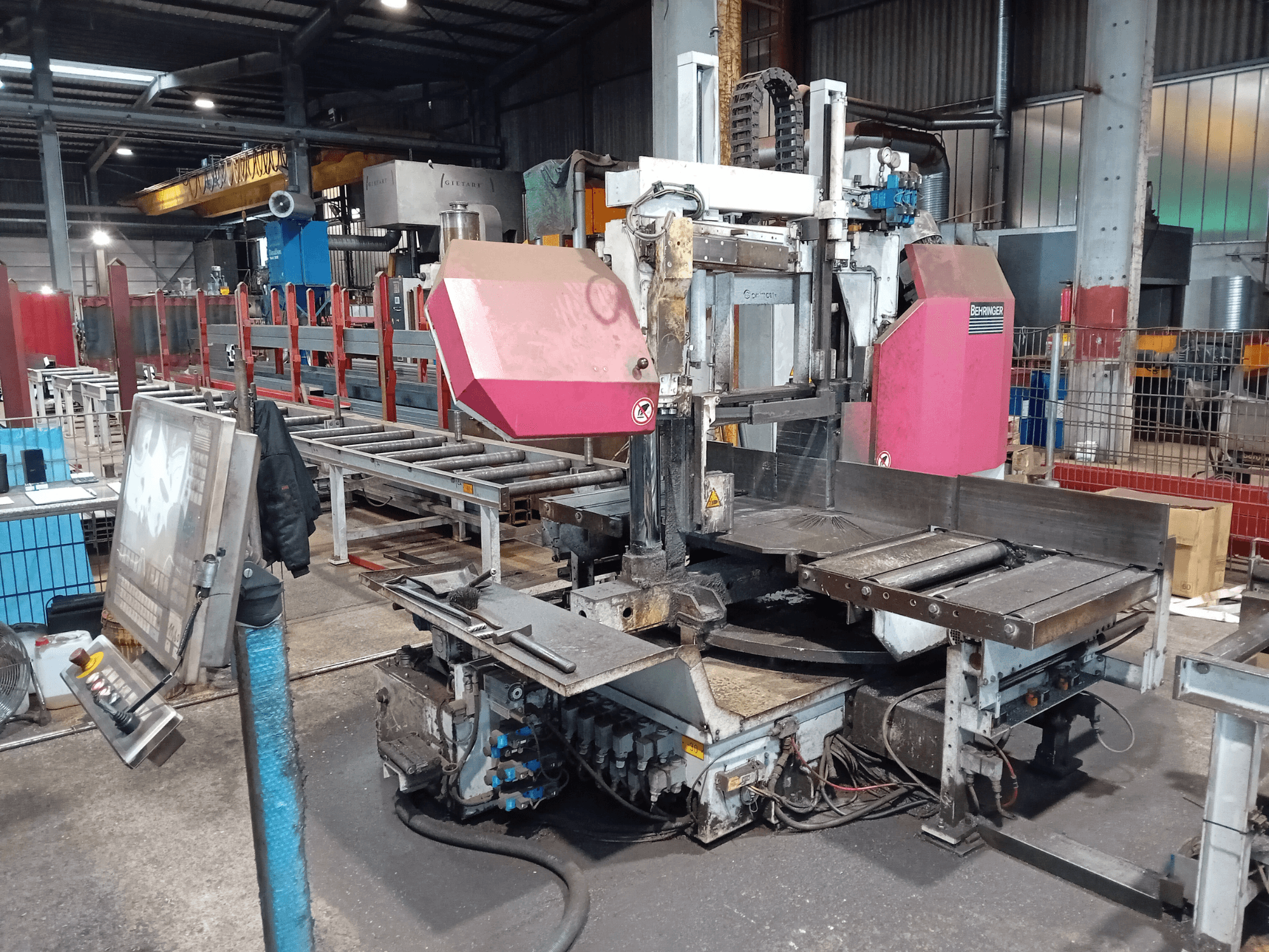 Behringer-Bandsägemaschine in einer Fabrik, Vorderansicht, mit einem großen Sägeblatt und einem Bedienfeld mit Tasten.