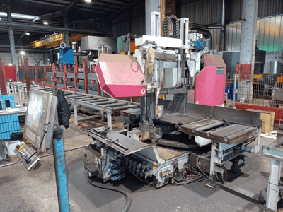 Behringer-Bandsägemaschine in einer Fabrik, Vorderansicht, mit einem großen Sägeblatt und einem Bedienfeld mit Tasten.
