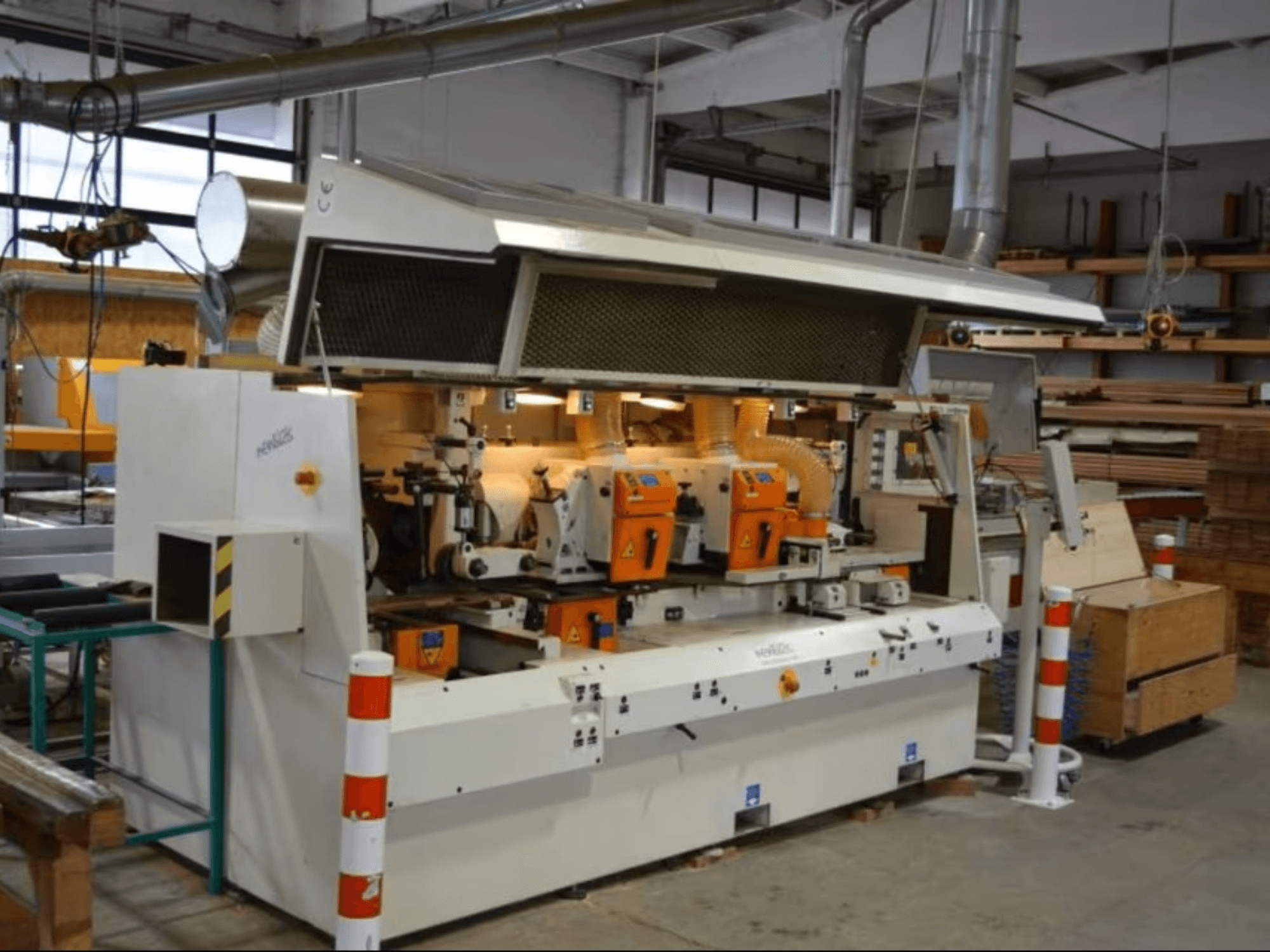 PENIGAS wood processing machine, front view, featuring dual orange cutting heads and dust extraction system in a workshop setting.