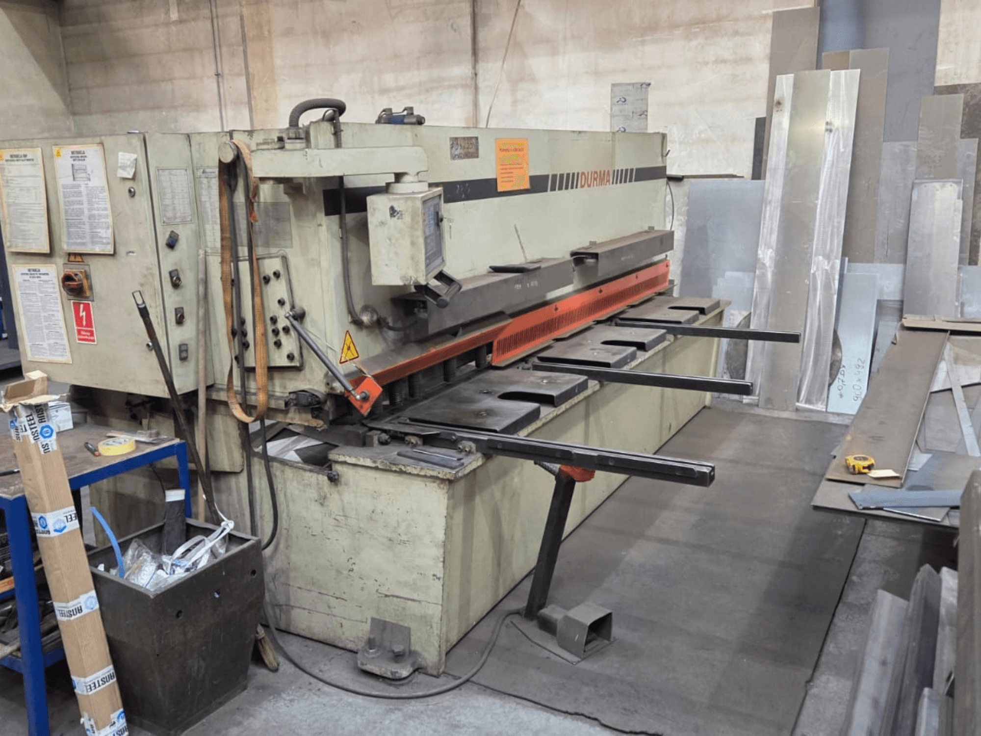 Hydraulische Schermaschine Durma SB 3060, Vorderansicht, zeigt Bedienelemente, Schneidmesser und Bleche im Arbeitsbereich.