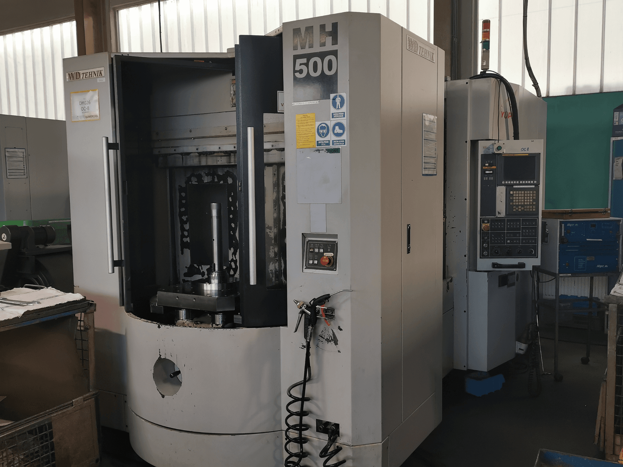MH 500 machining center in a workshop, front view; visible control panel and workpiece holder inside the machine.