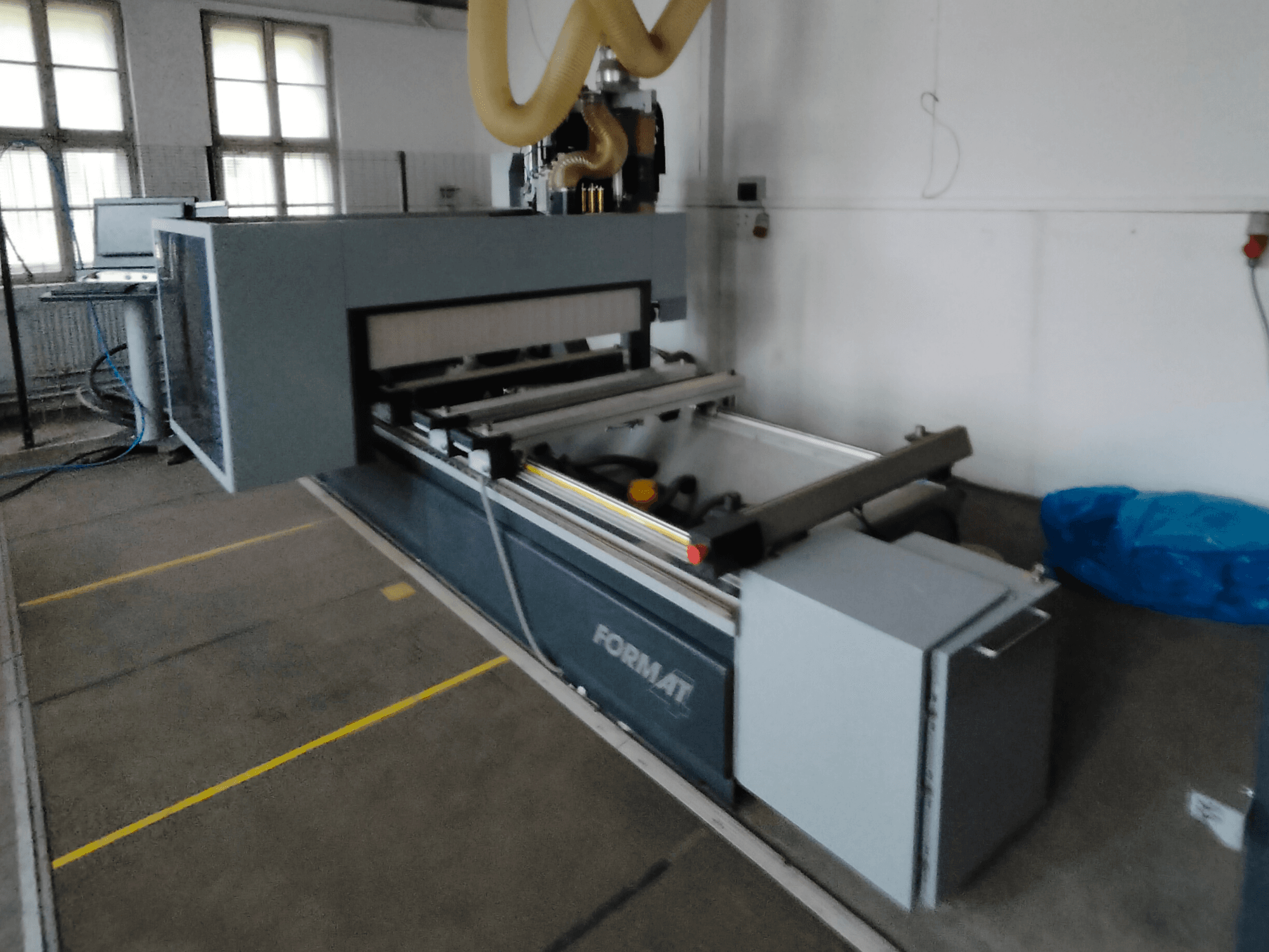 Vorderansicht einer Format-CNC-Maschine mit grauem Gehäuse, mit Führungsschienen und sichtbarem Bedienfeld.