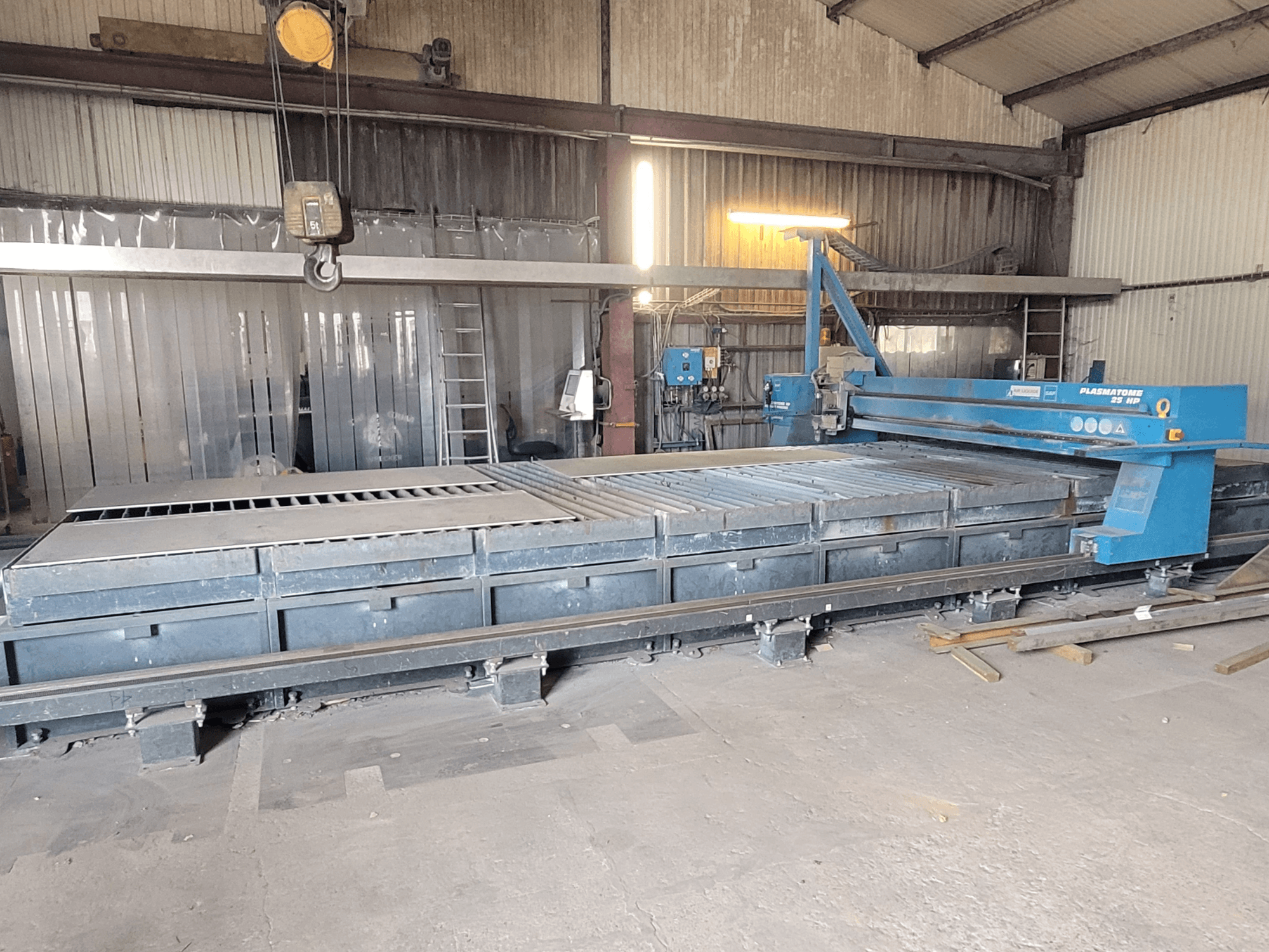 SAF Plasmatone 25Hp Plasmaschneidanlage, Seitenansicht, zeigt das Schneidbett und die Betriebskomponenten in einer industriellen Umgebung.