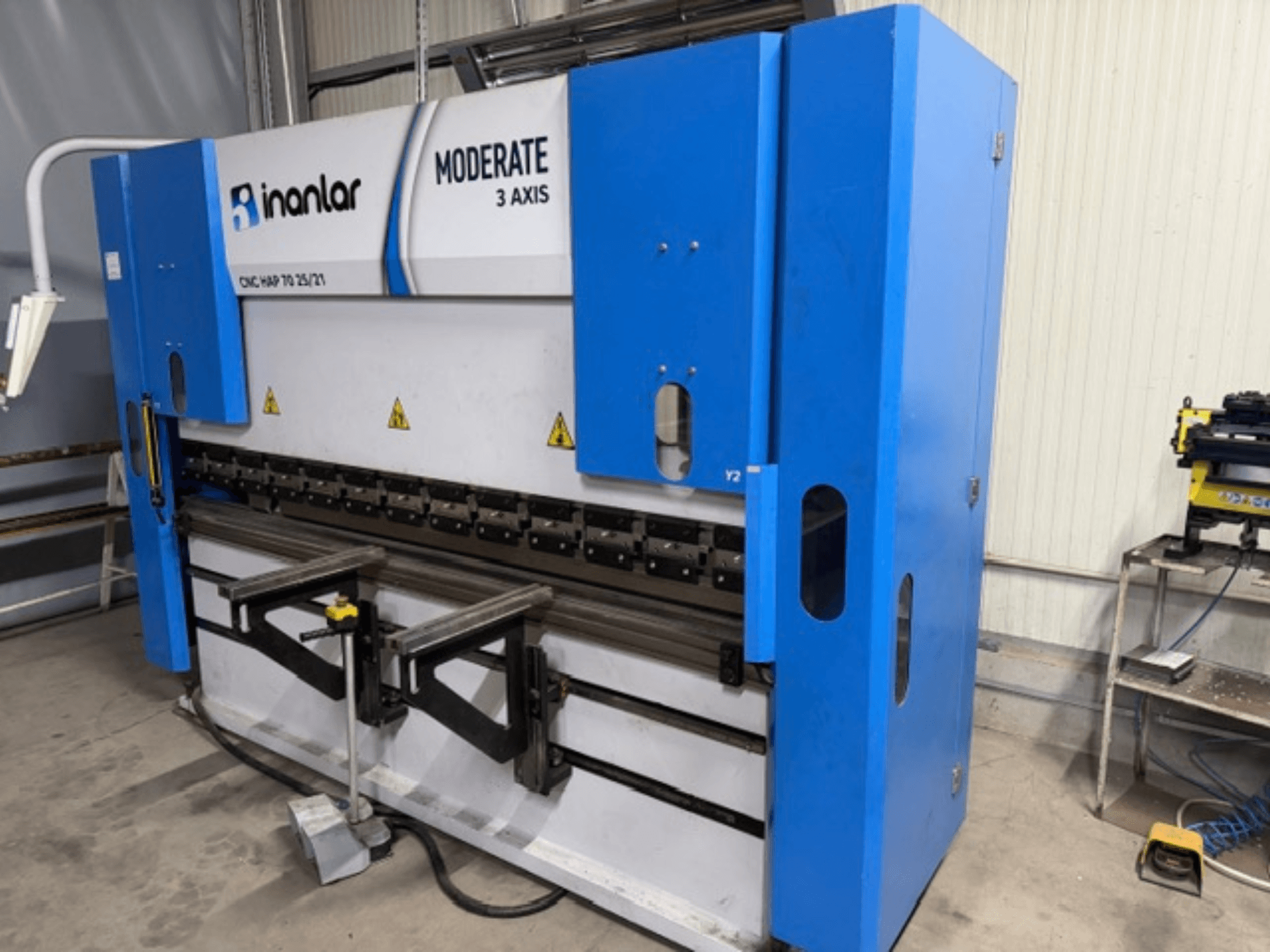 Inanlar Moderate 3-Achsen-CNC-Maschine in blau, Vorderansicht, mit sichtbaren Bedienhebeln und Sicherheitsschildern am Gehäuse.