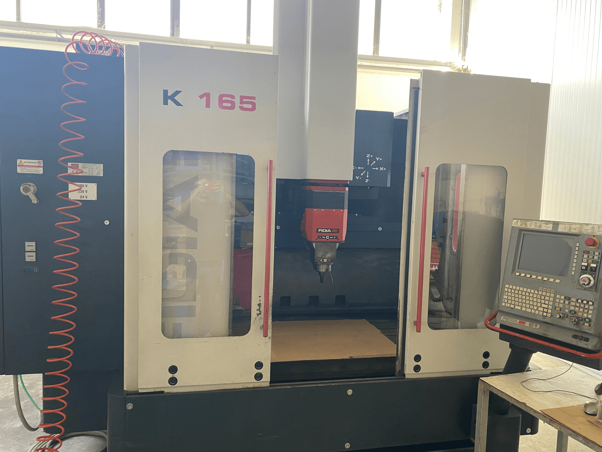 CNC-Maschine Fidia K 165 mit roter Spindel und Bedienpult, von vorne gesehen, in einer gut beleuchteten Werkstattumgebung.