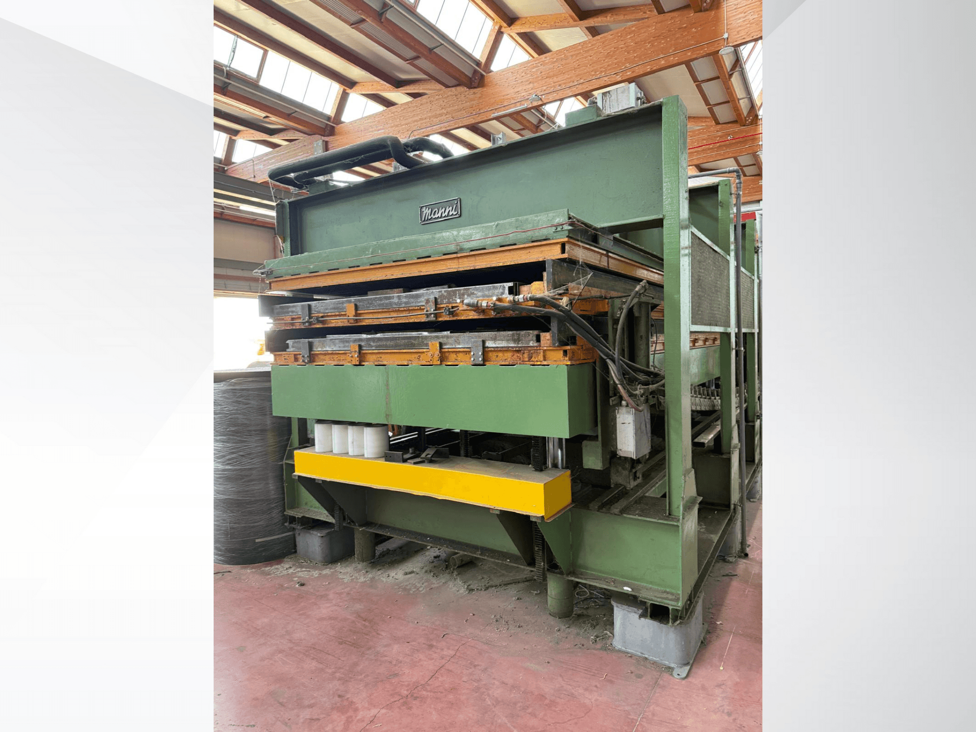 Manni hydraulic press, side view, featuring green metal body, yellow base, and multiple hydraulic lines visible.