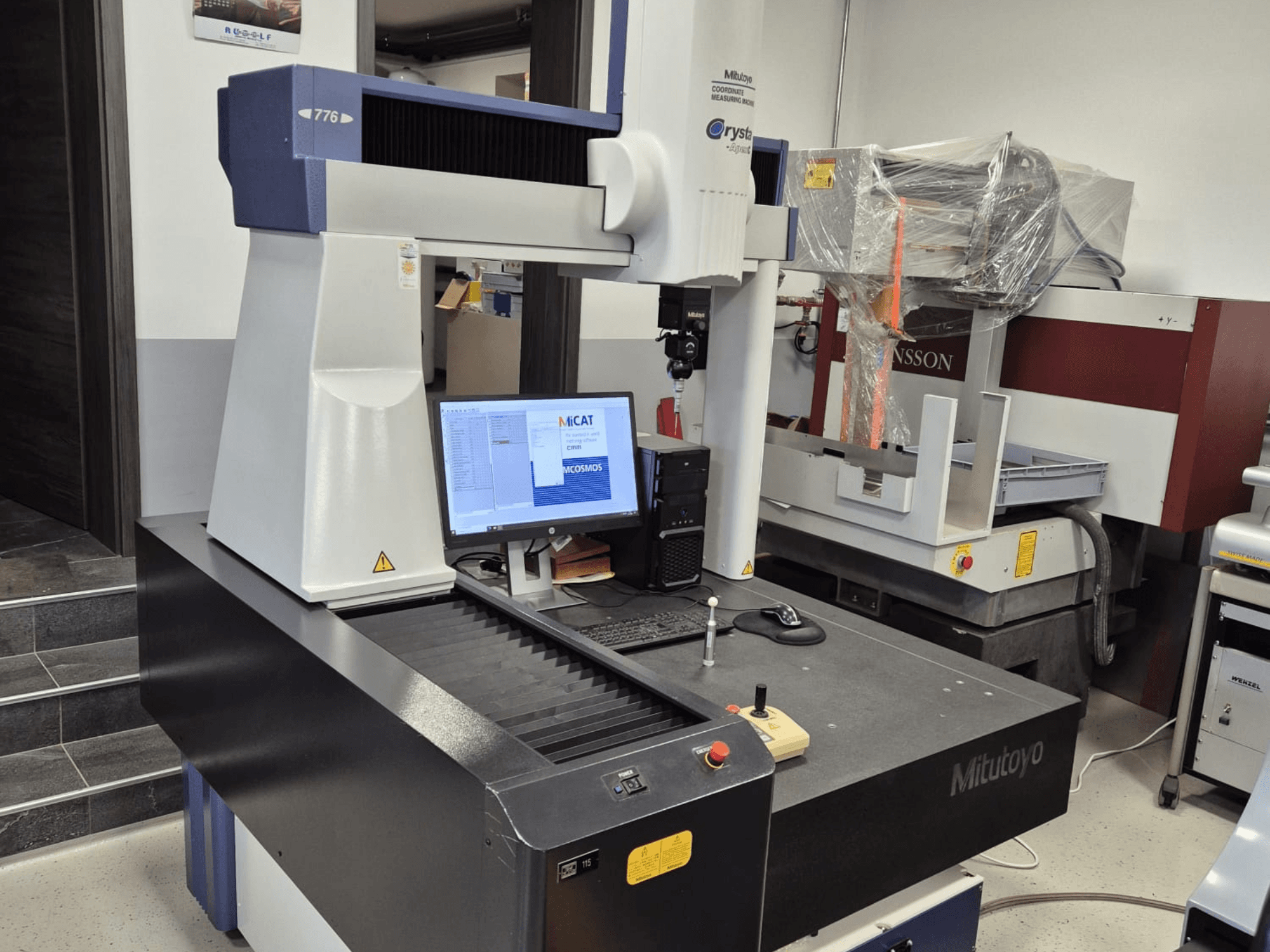 Mitutoyo-Koordinatenmessgerät Modell 776 in der Vorderansicht, mit einem Monitor, auf dem Messsoftware und Bedienelemente zu sehen sind.