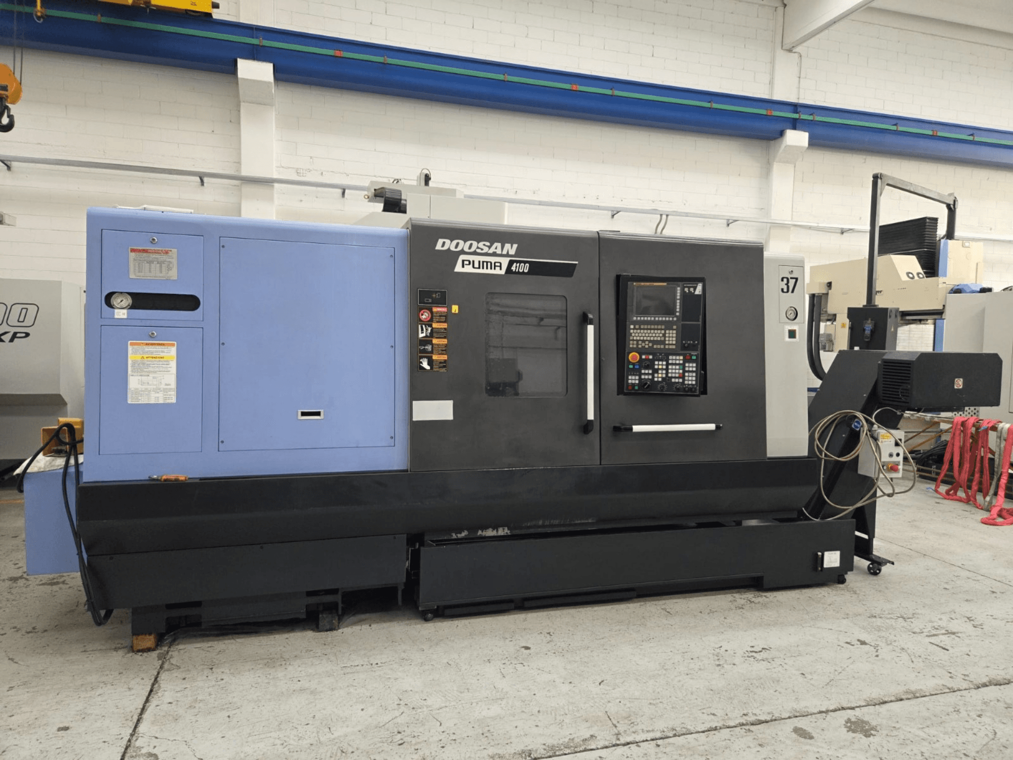 Doosan Puma 4100 CNC-Drehmaschine, Vorderansicht; mit Bedienfeld, blauem Aggregat und detaillierten Beschriftungen zur Bedienerführung.
