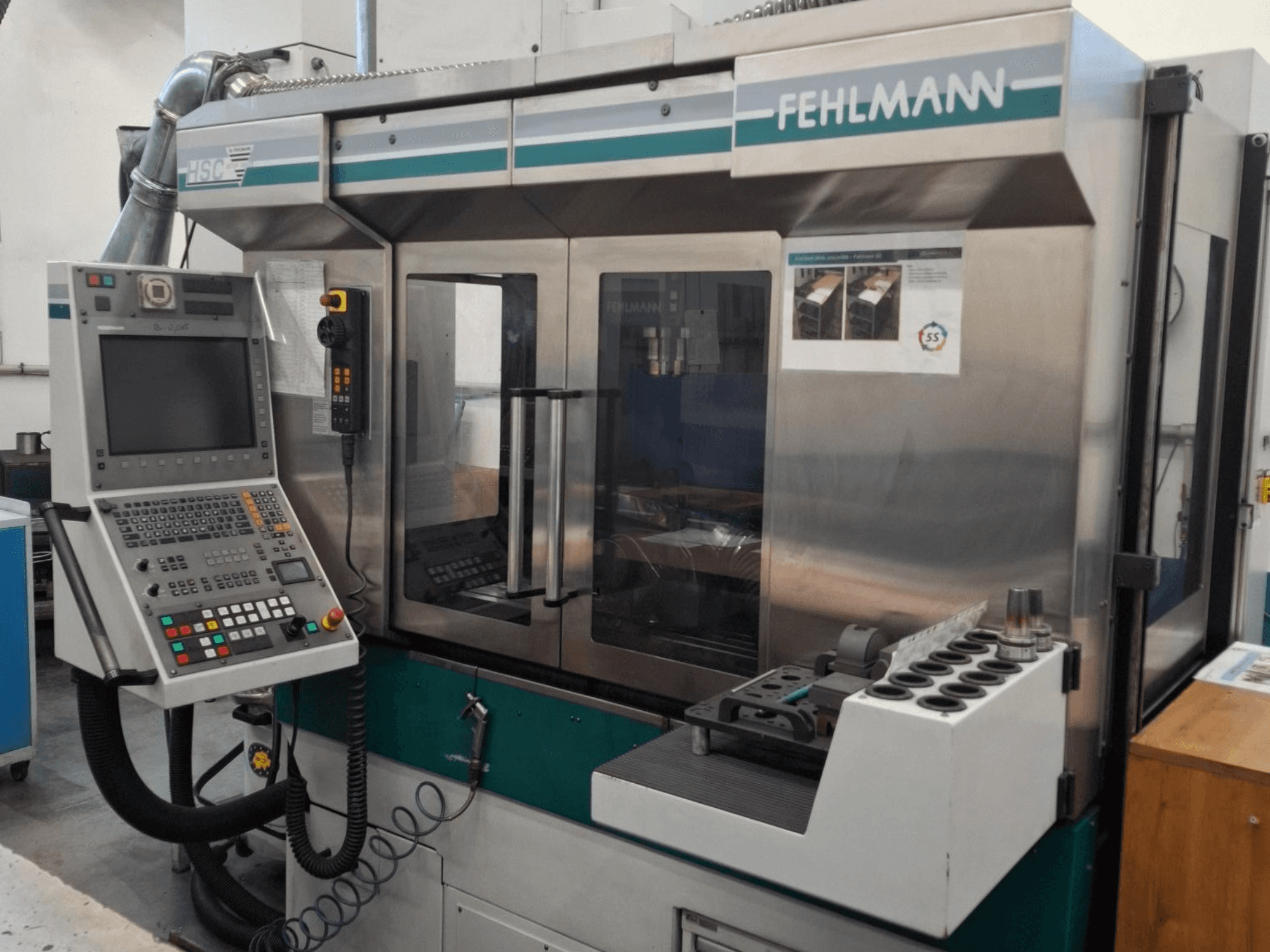 Fehlmann HSC 20 CNC-Maschine, Vorderansicht, mit Bedienfeld, Metallgehäuse und Werkzeughalter mit mehreren Steckplätzen.