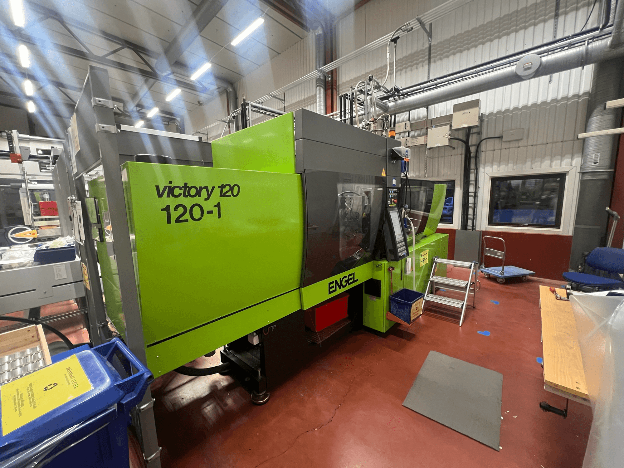 Grüne ENGEL Victory 120-1 Spritzgießmaschine, Vorderansicht, mit Bedienfeld und Stufen, in einer Industrieumgebung.