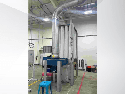 Großes industrielles Belüftungssystem, Vorderansicht, mit glänzenden Metallrohren und blauem Sockel, in einer großen Lagerhalle.