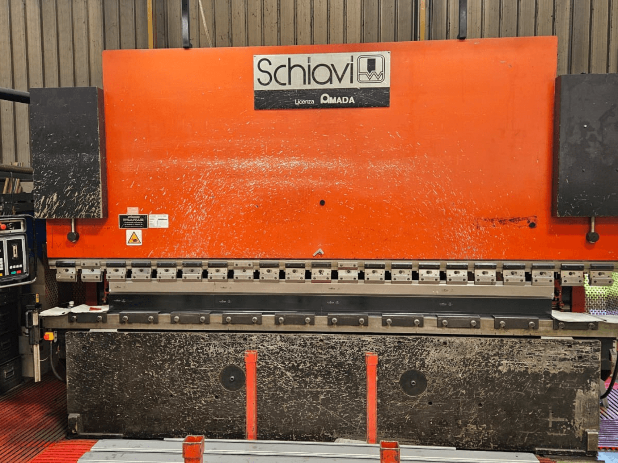 Schiavi Amada Metallbiegemaschine, Vorderansicht, mit orangefarbenem Gehäuse, Bedienfeld auf der linken Seite und mehreren Biegewerkzeugen sichtbar.