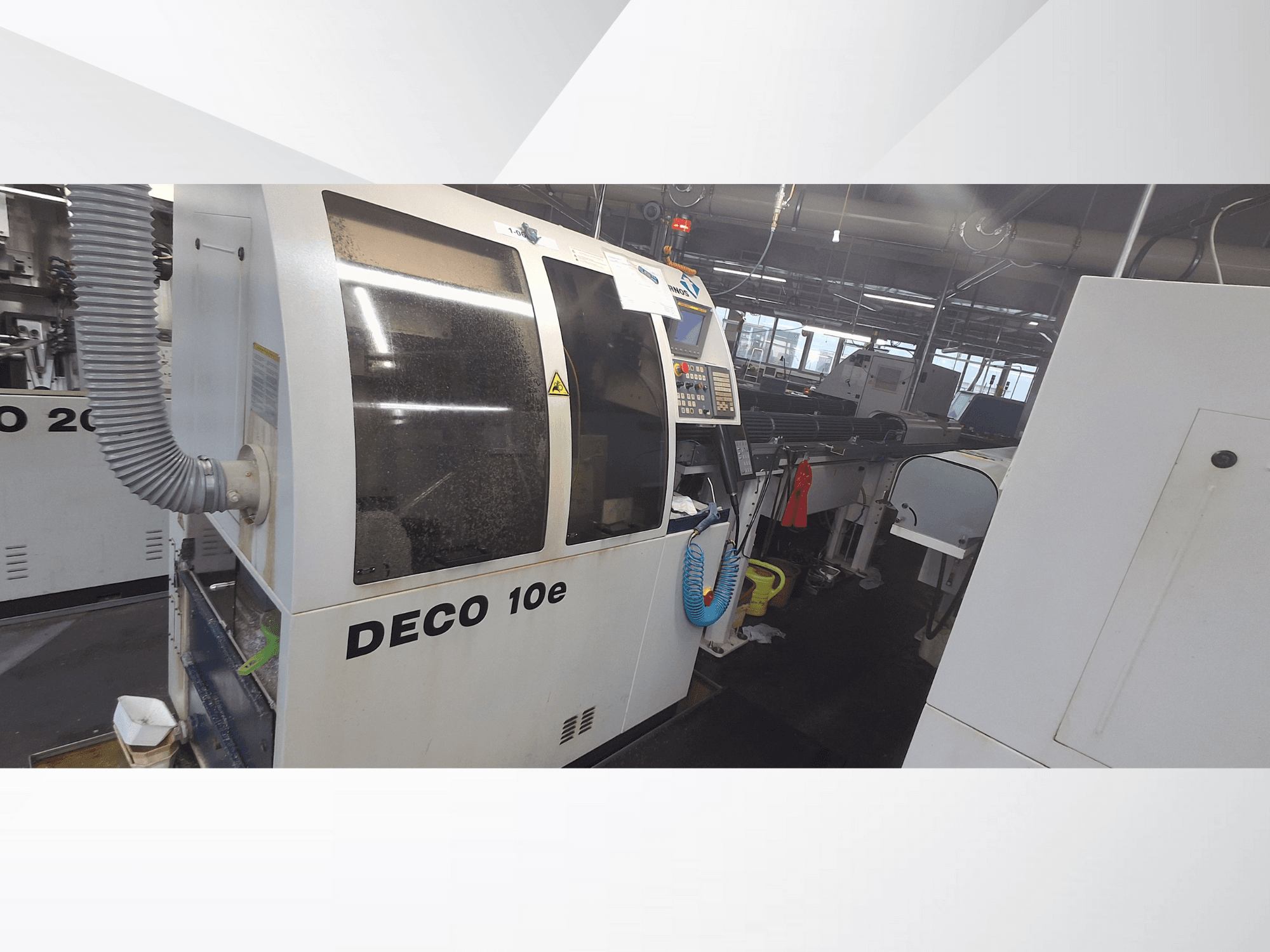 DECO 10e Maschine in einer Werkstatt; Seitenansicht mit Bedienfeld und Lüftungsschlauch, im Hintergrund unscharfe Maschinen.