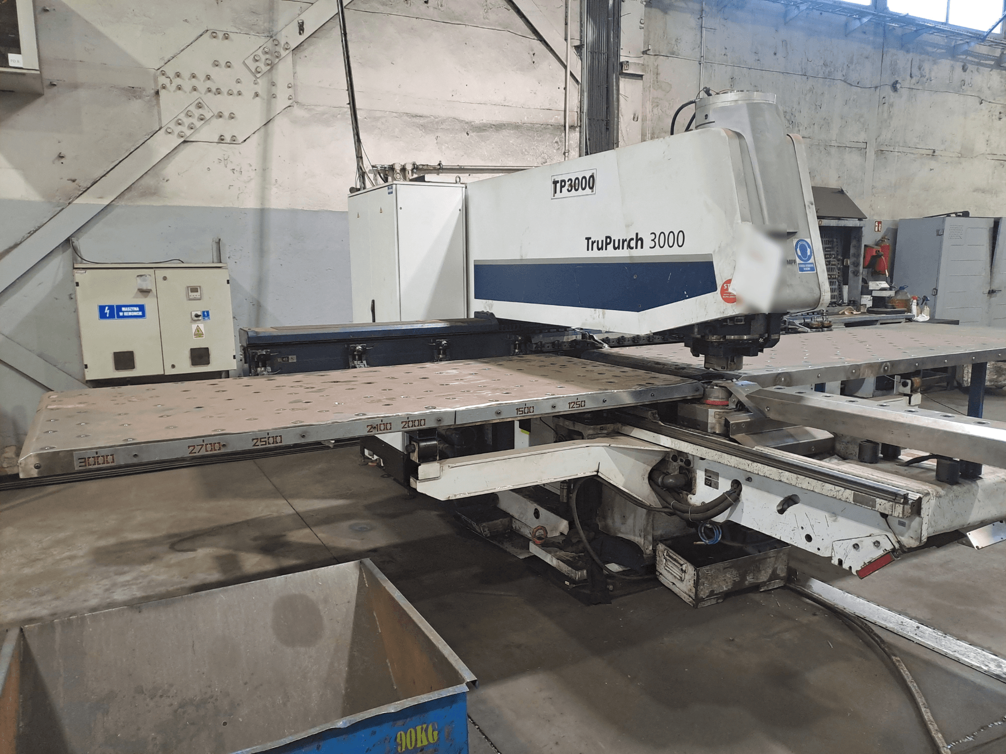 TruPunch 3000 CNC-Maschine von vorne, mit großer Metallplatte und Messmarkierungen, in einer Industrieumgebung.