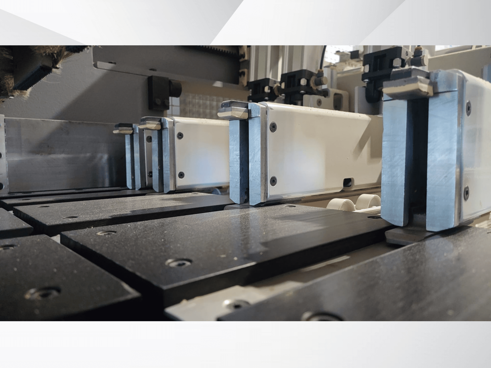 Nahaufnahme des Spannmechanismus einer Präzisionsmaschine mit Metallbacken, schwarzen Arbeitsflächen und sichtbaren Führungsschienen.