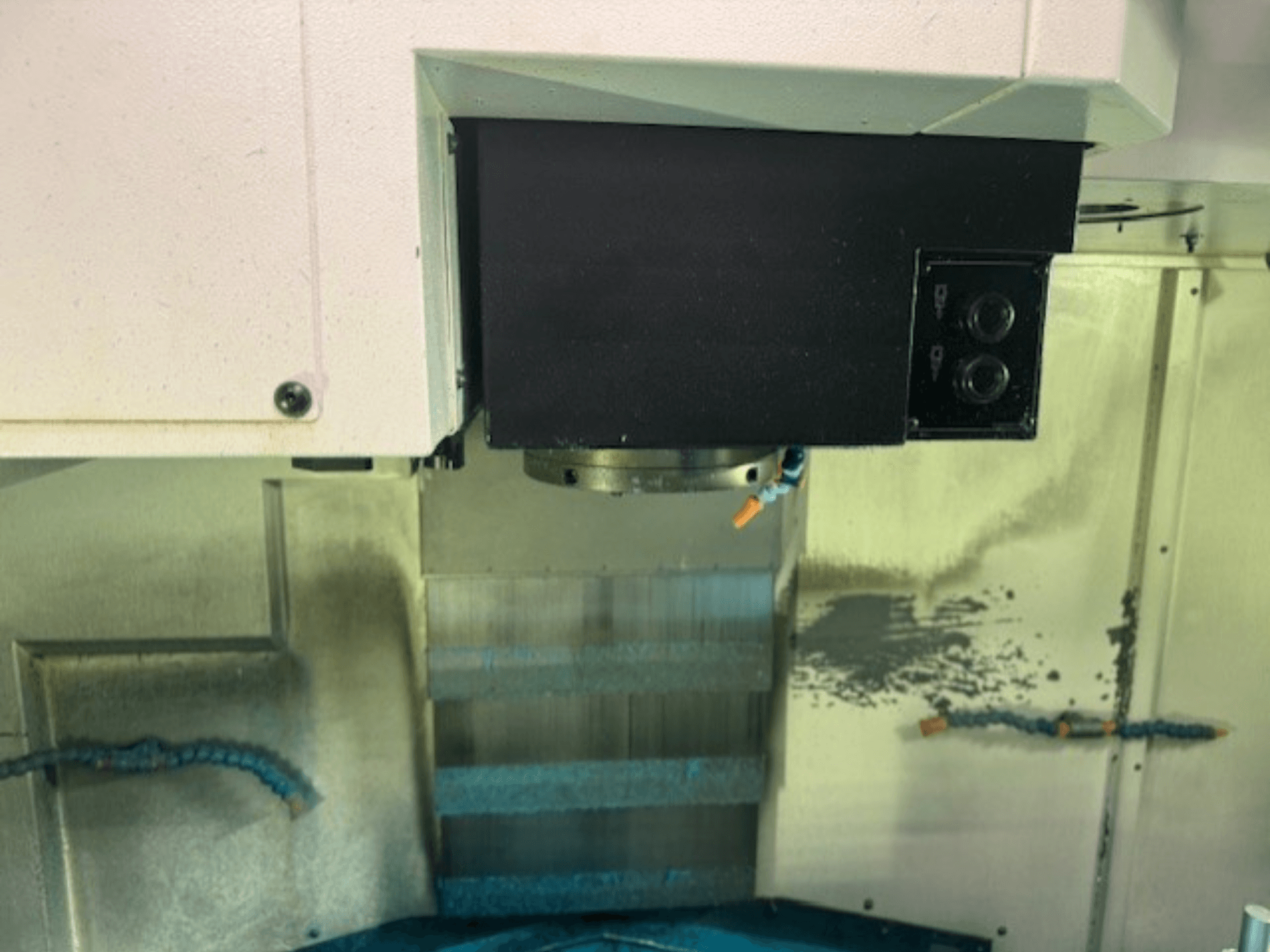 Nahaufnahme eines CNC-Fräsmaschinen-Bedienfelds und eines Werkzeughalters, die Markendetails, Tasten und Arbeitsfläche zeigen.