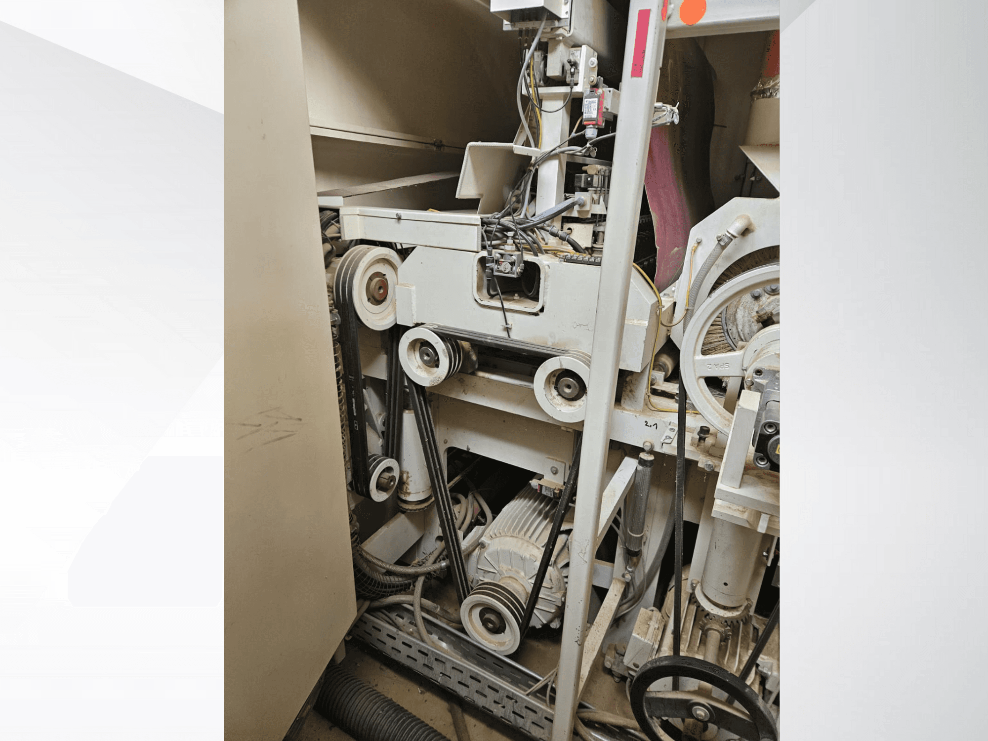 Industrial machine interior with belts and pulleys, featuring a motor and wiring, viewed from the side.