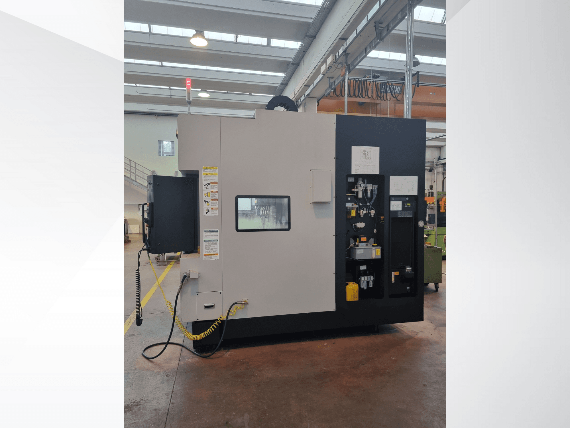 Industrial machine from a side view, features a control panel with buttons, indicators, and a safety warning label.