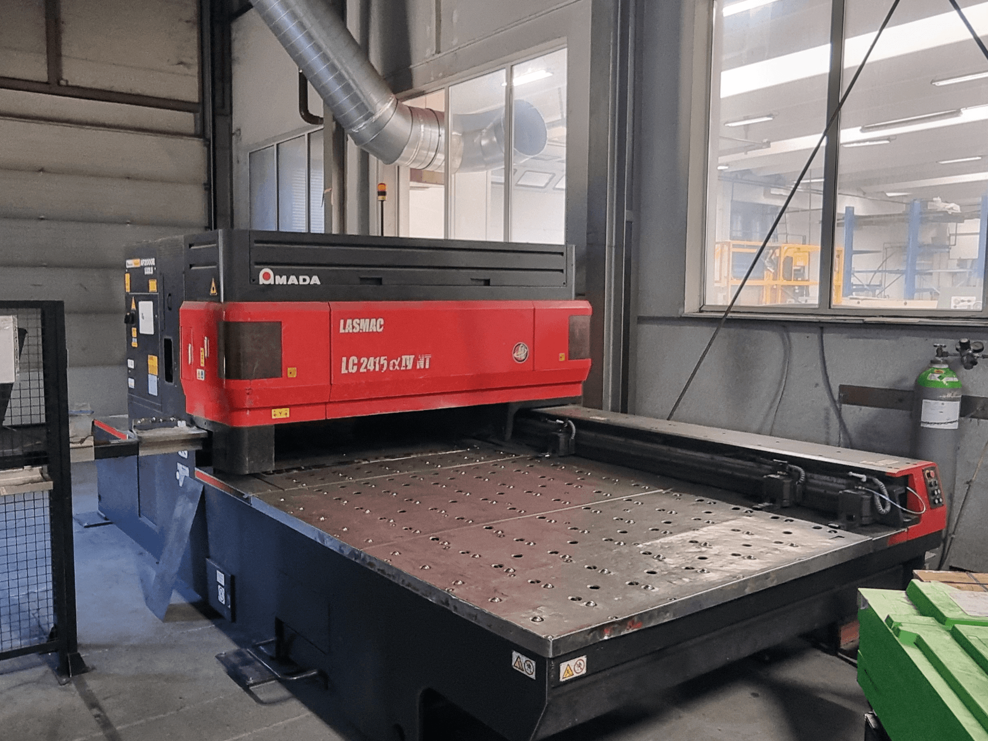 Amada LASMAC LC 2415 αⅡ NT Laserschneidmaschine in rot und schwarz, Vorderansicht, mit angetriebenem Schneidbett und Präzisionssteuerung.